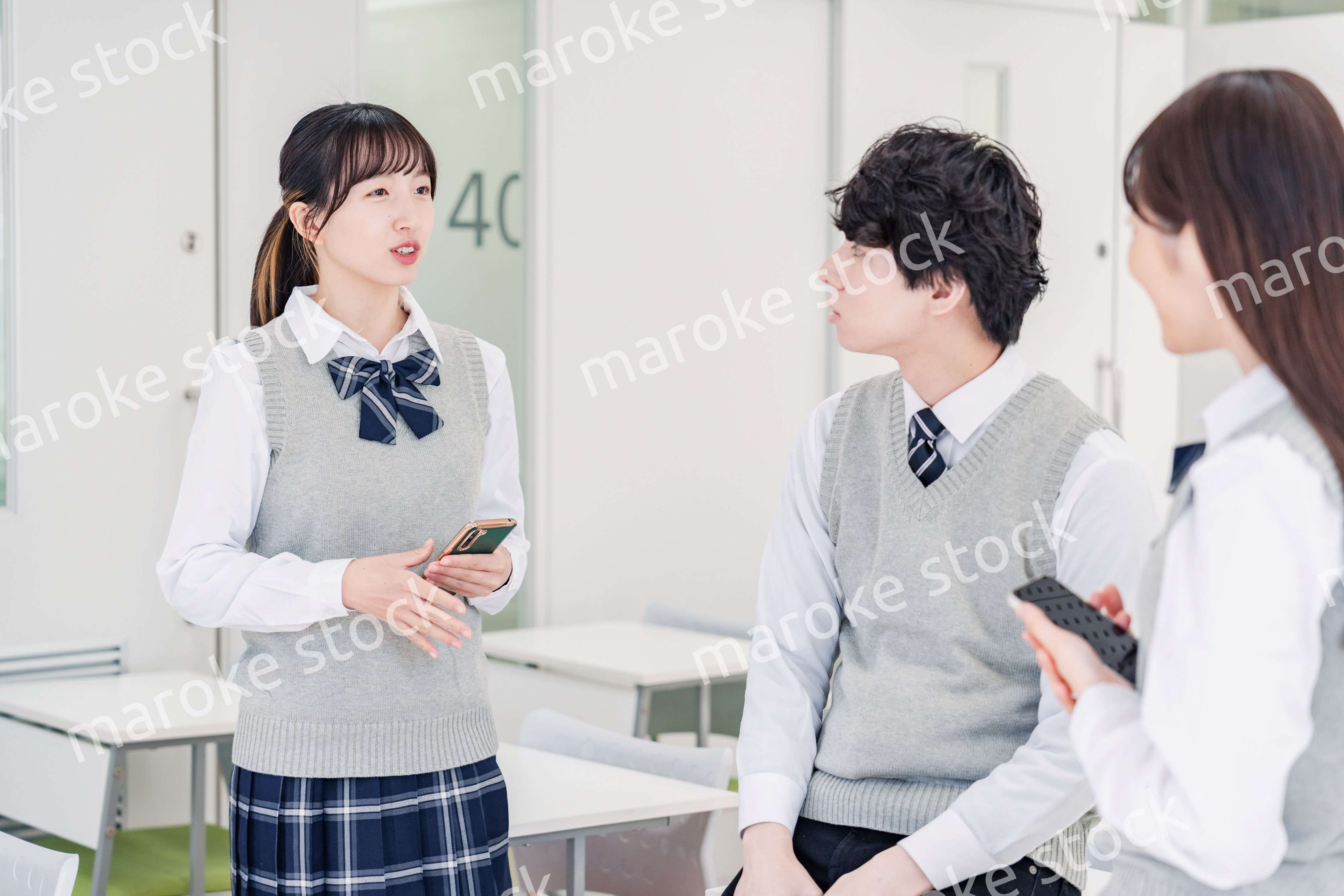 教室でクラスメイトと雑談をする高校生
