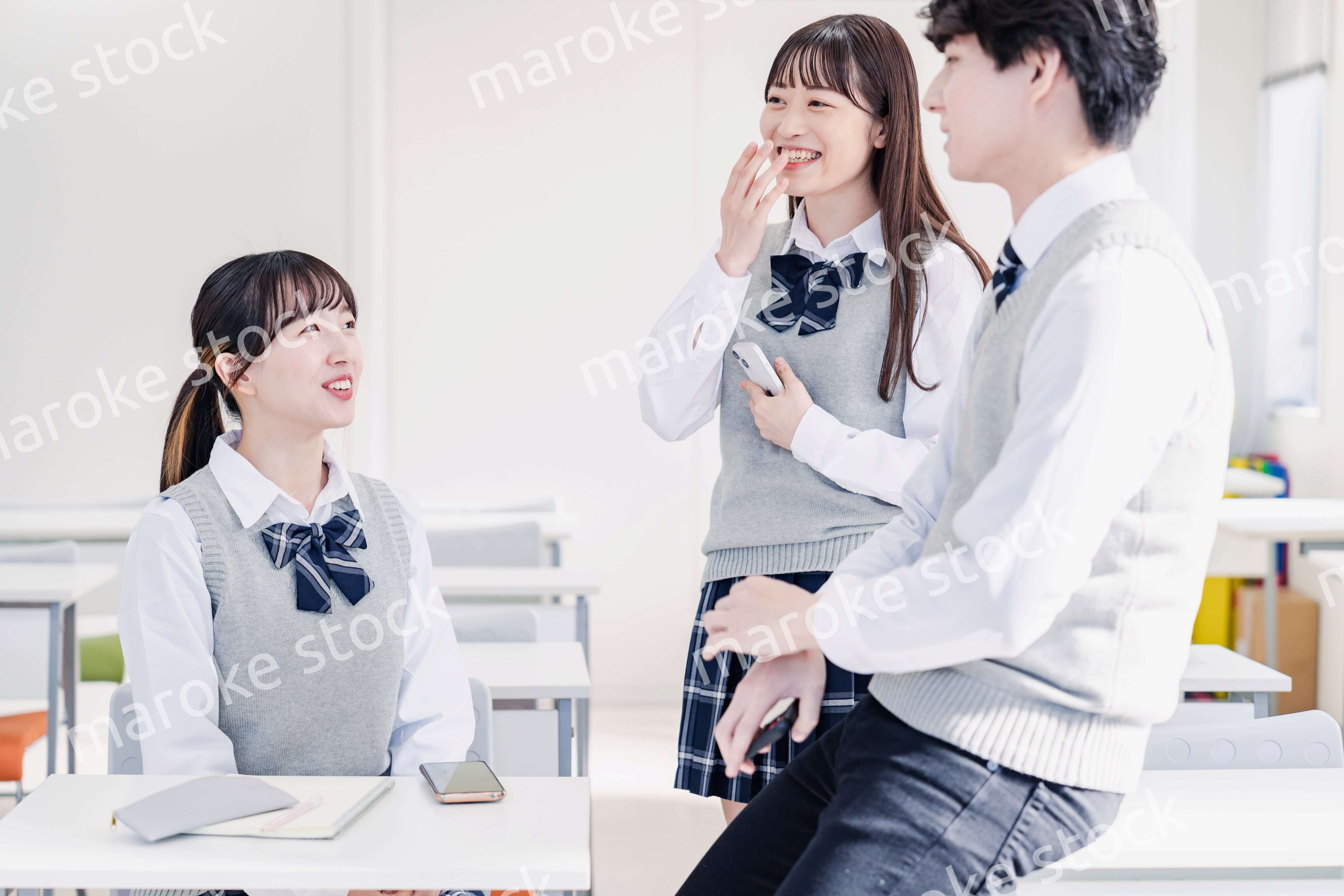 教室でクラスメイトと雑談をする高校生