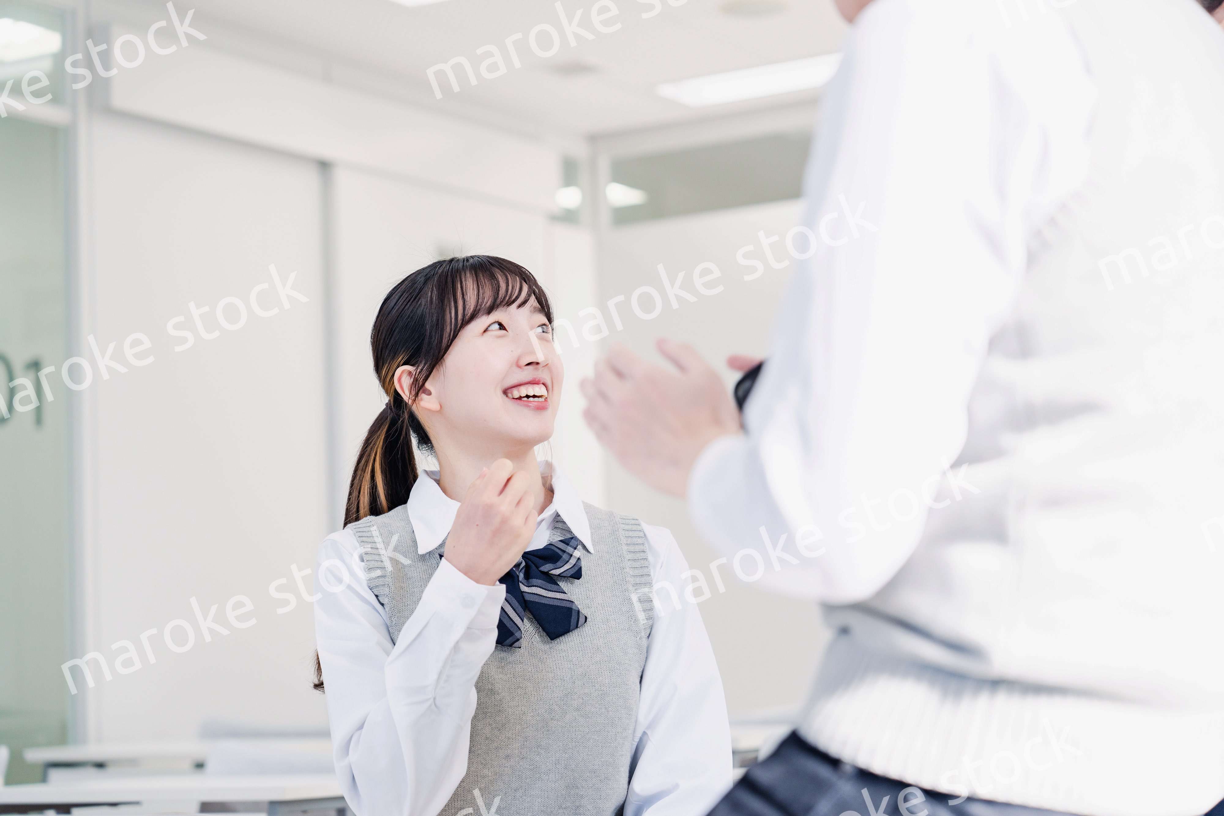 教室でクラスメイトと雑談をする高校生