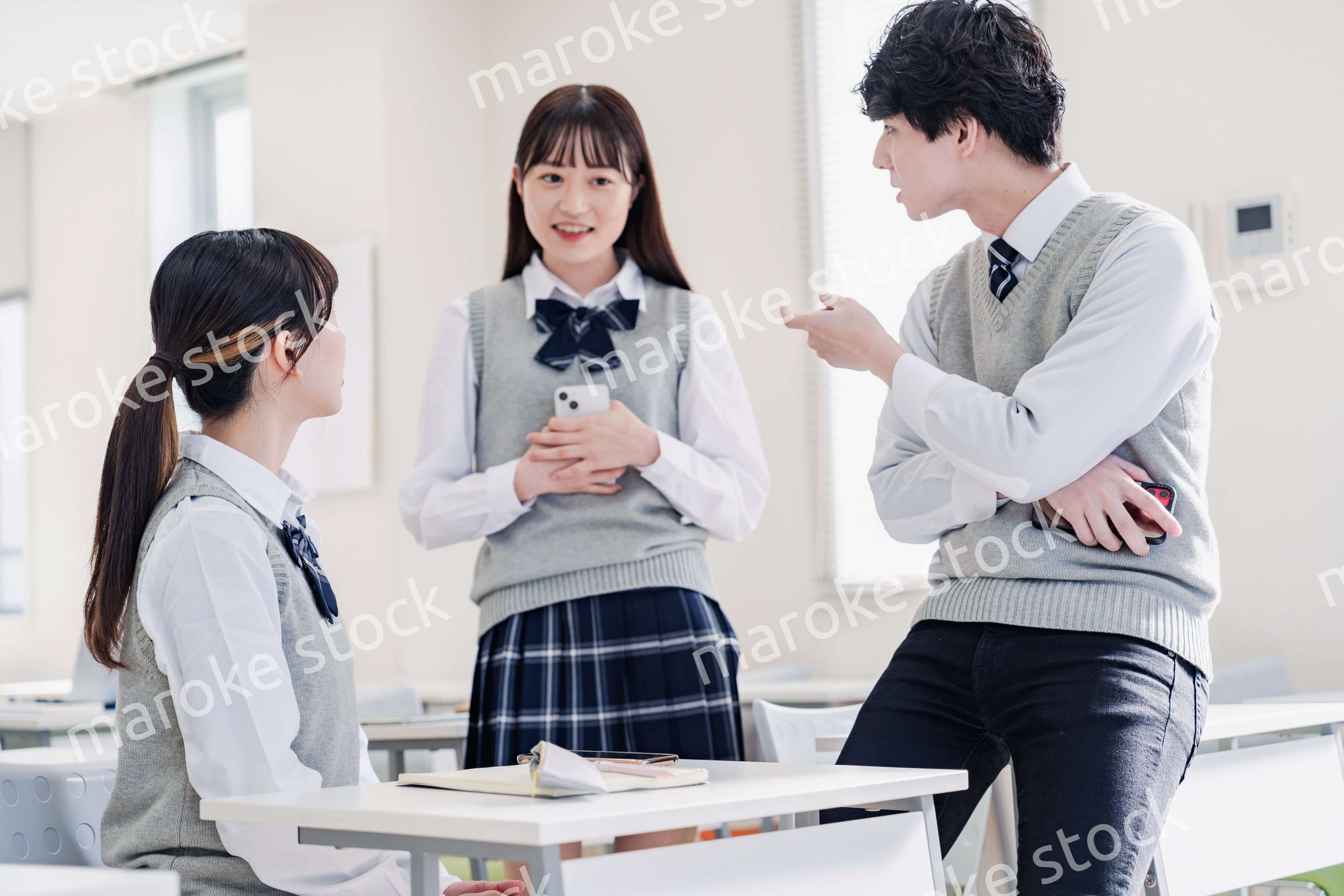 教室でクラスメイトと雑談をする高校生
