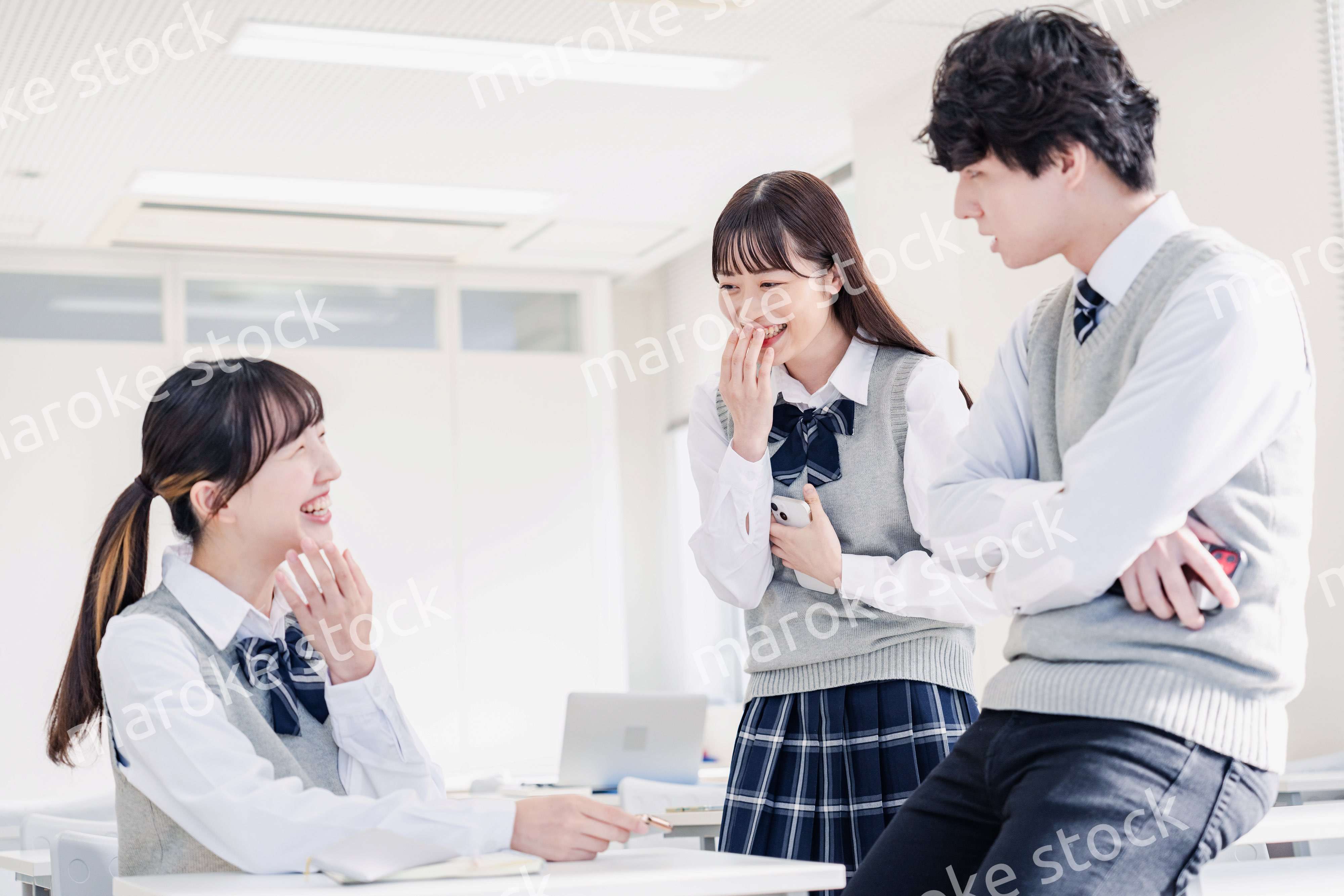 教室でクラスメイトと雑談をする高校生