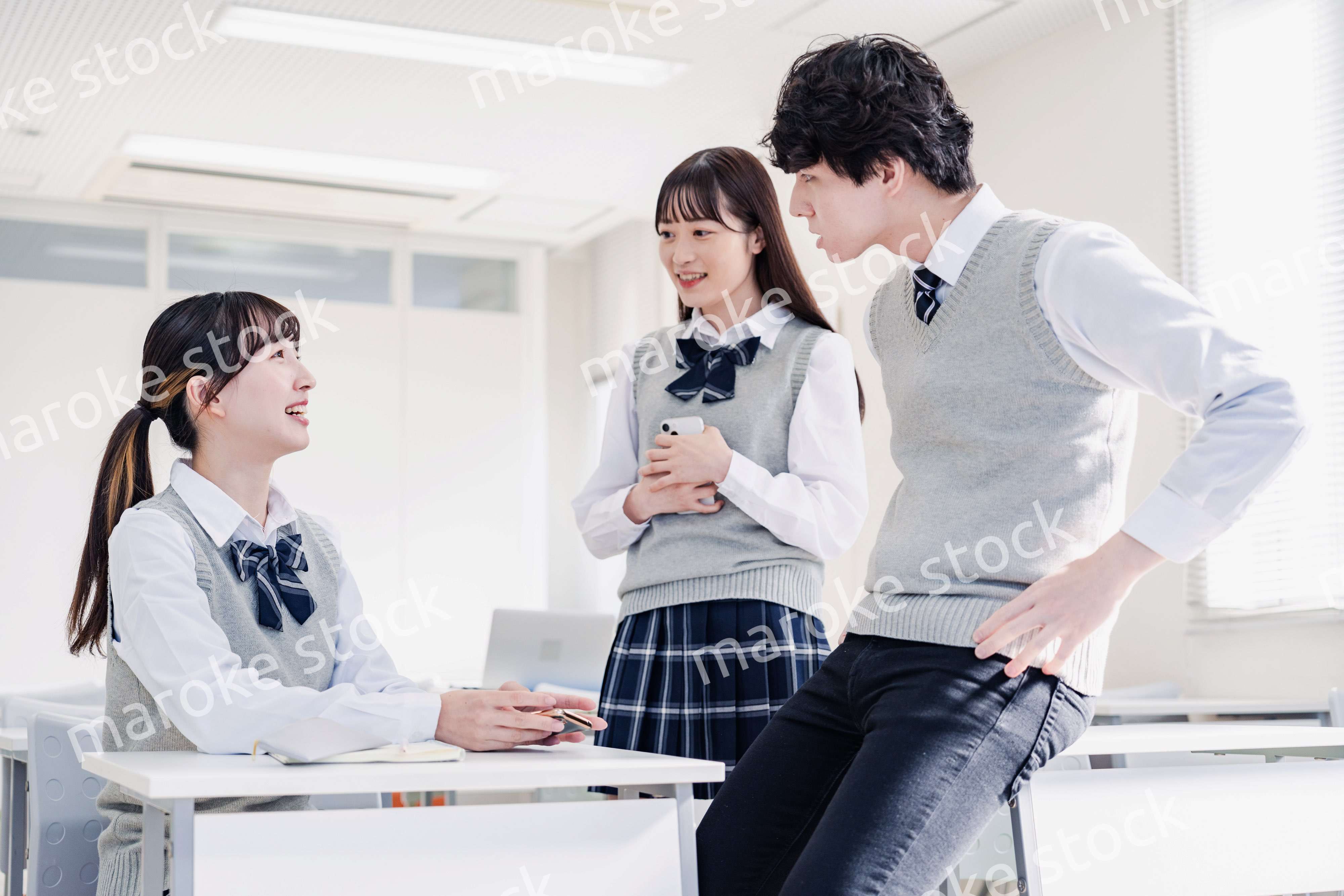 教室でクラスメイトと雑談をする高校生
