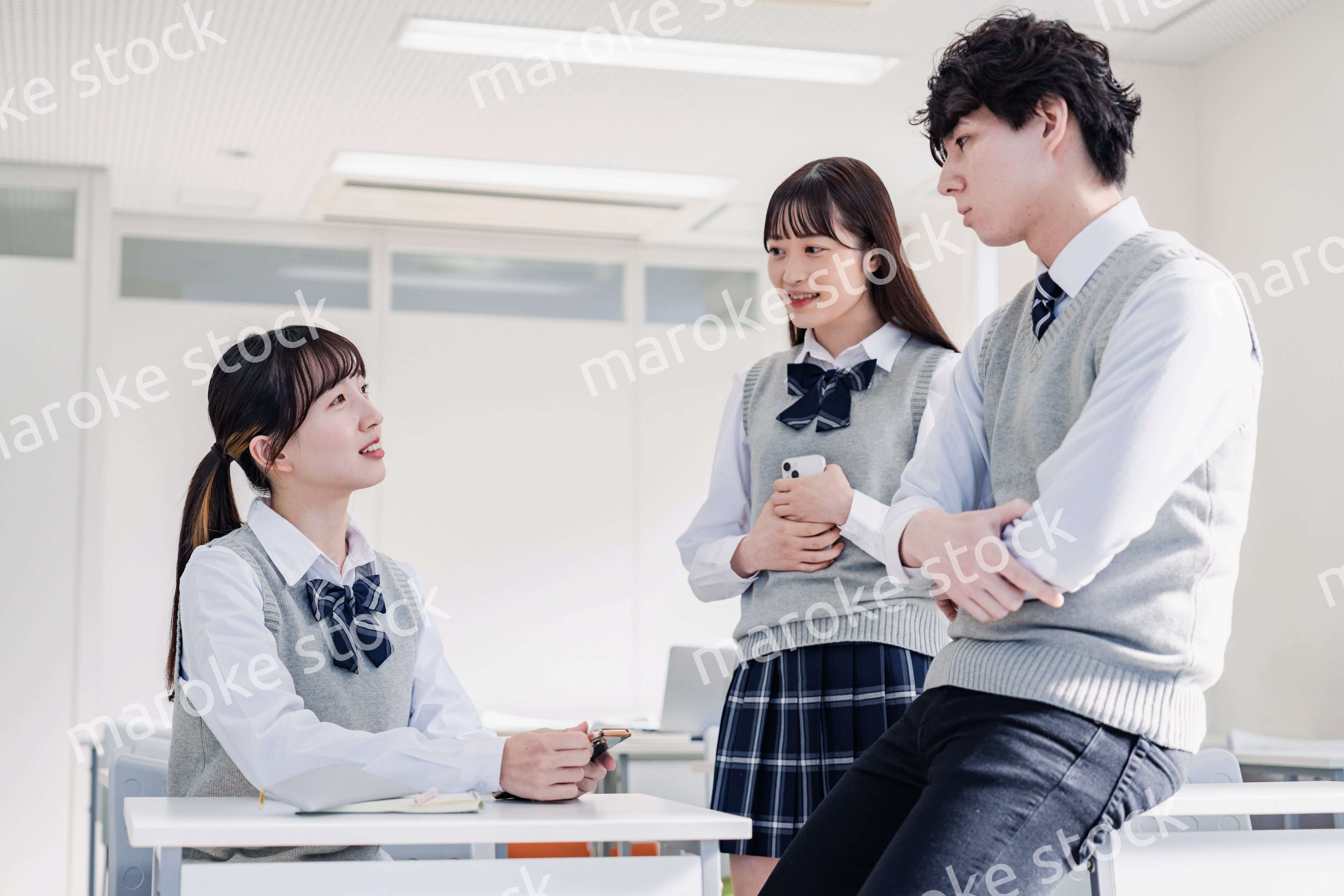教室でクラスメイトと雑談をする高校生