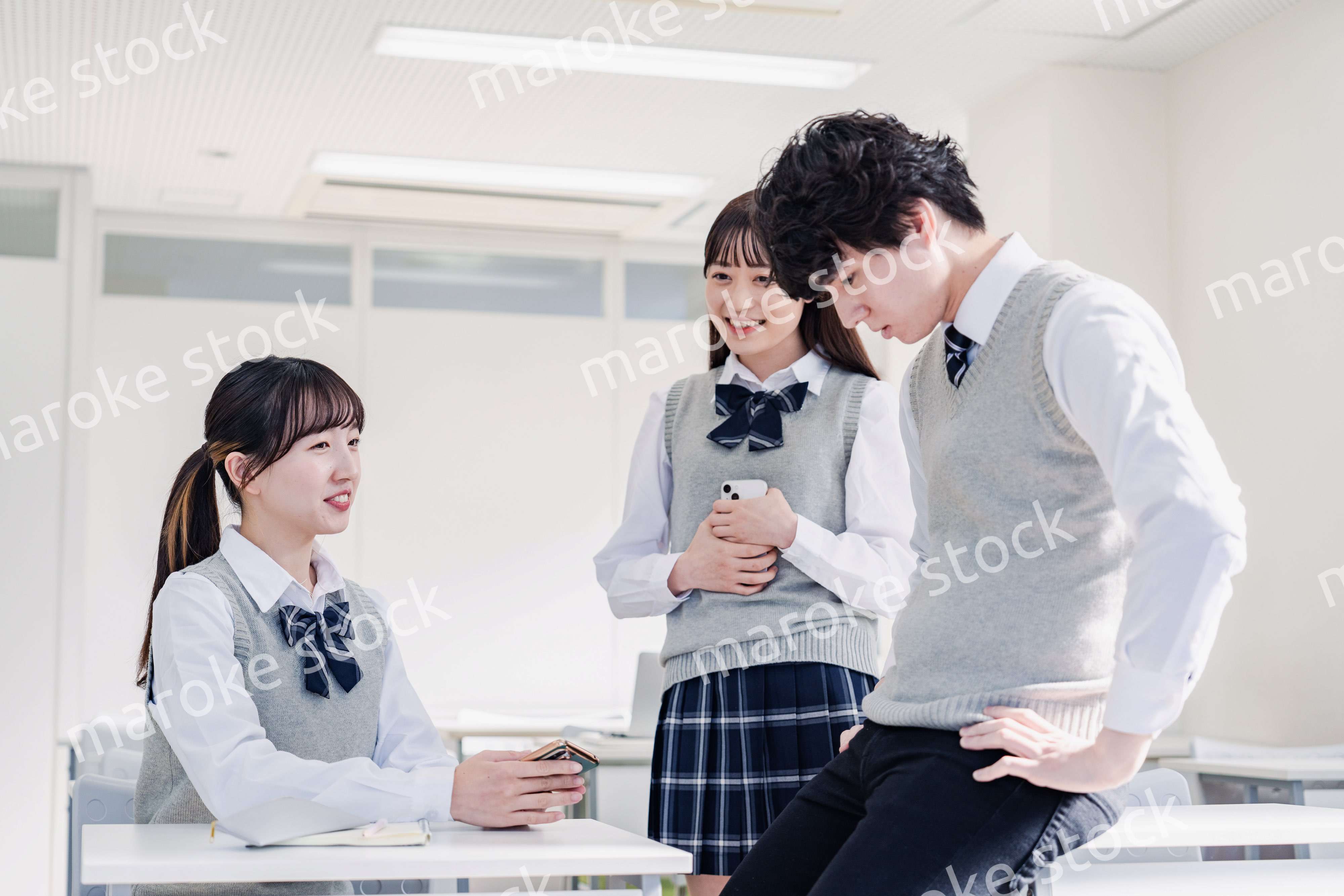 教室でクラスメイトと雑談をする高校生