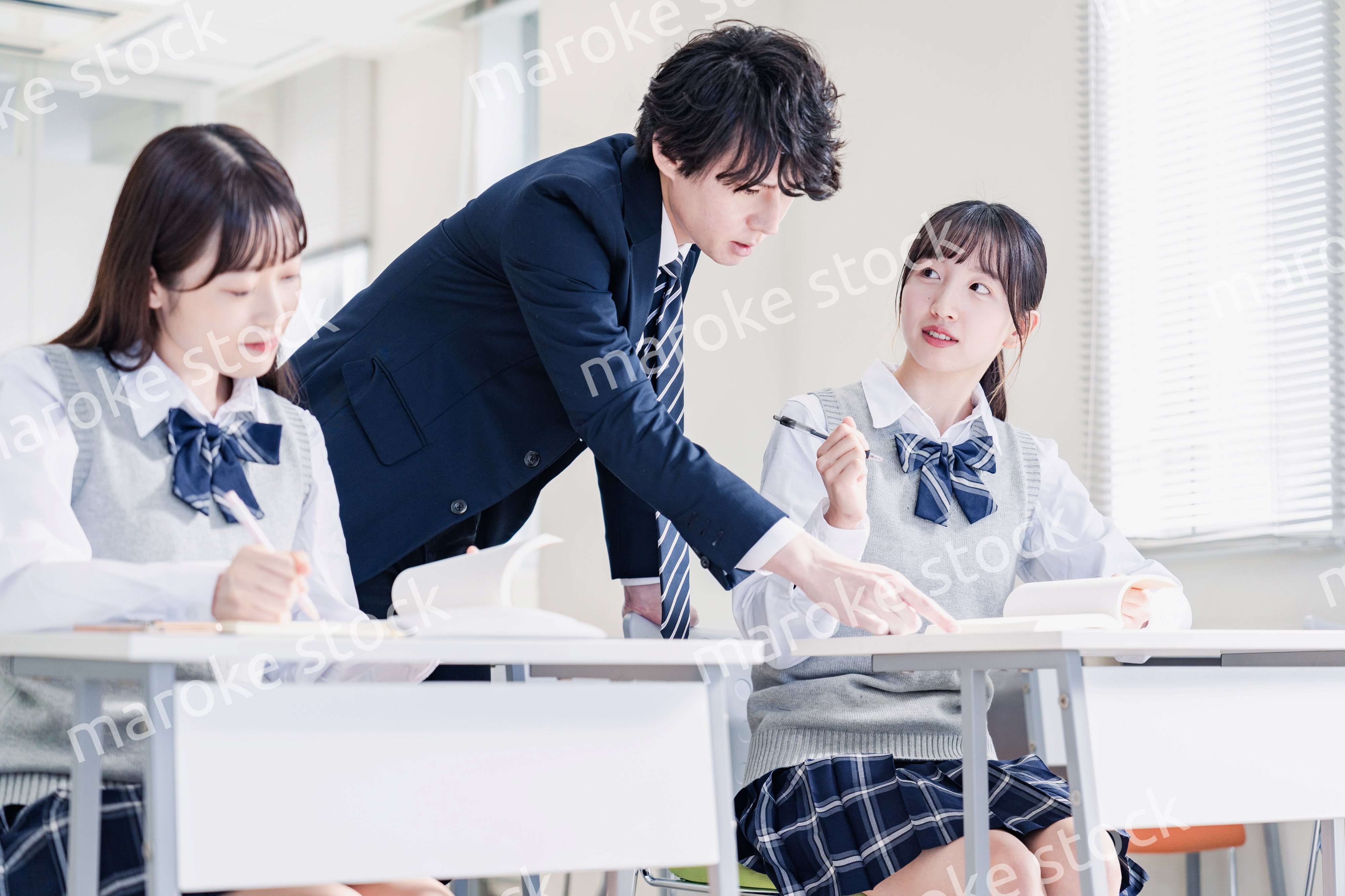 教室で先生に質問をする高校生