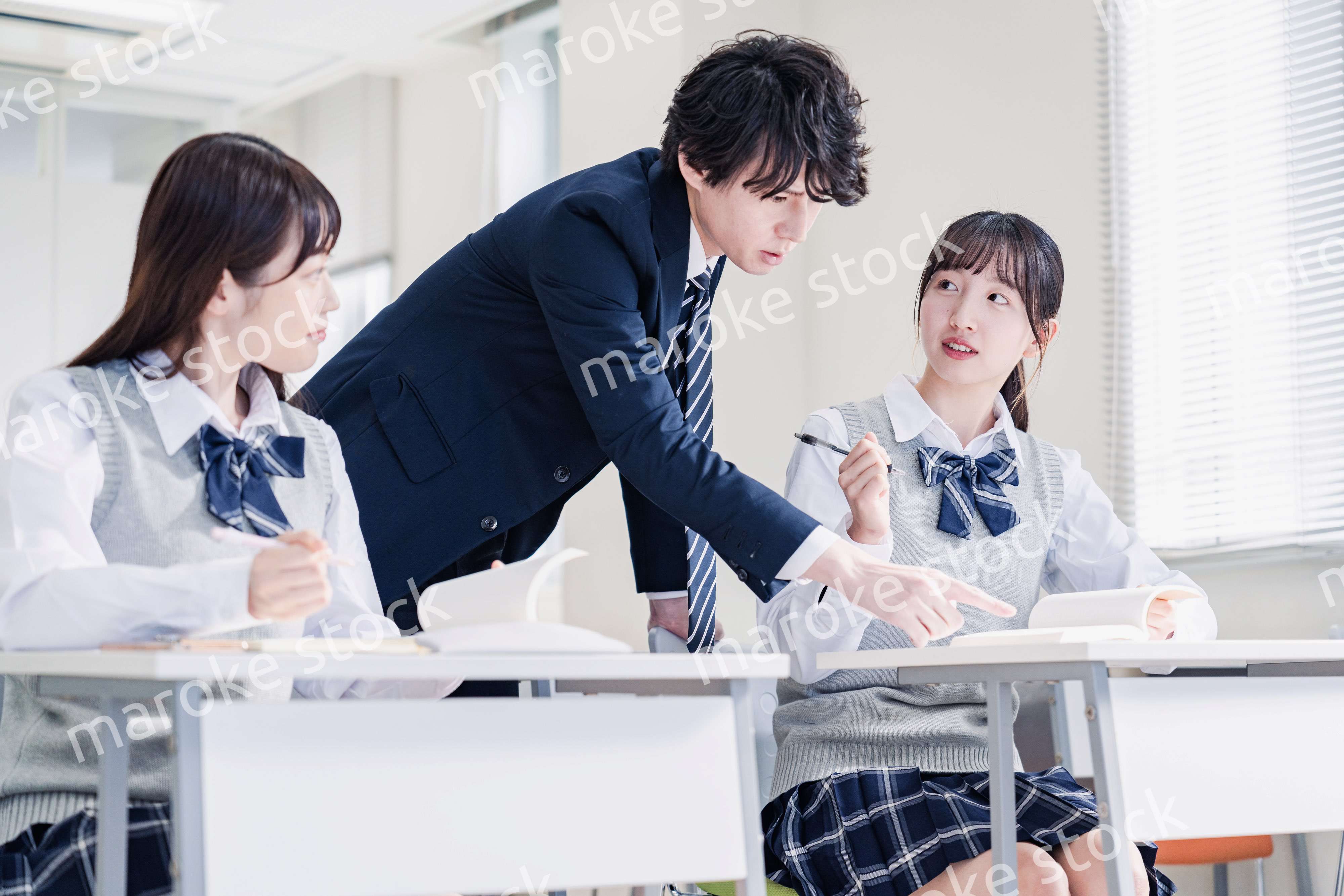 教室で先生に質問をする高校生