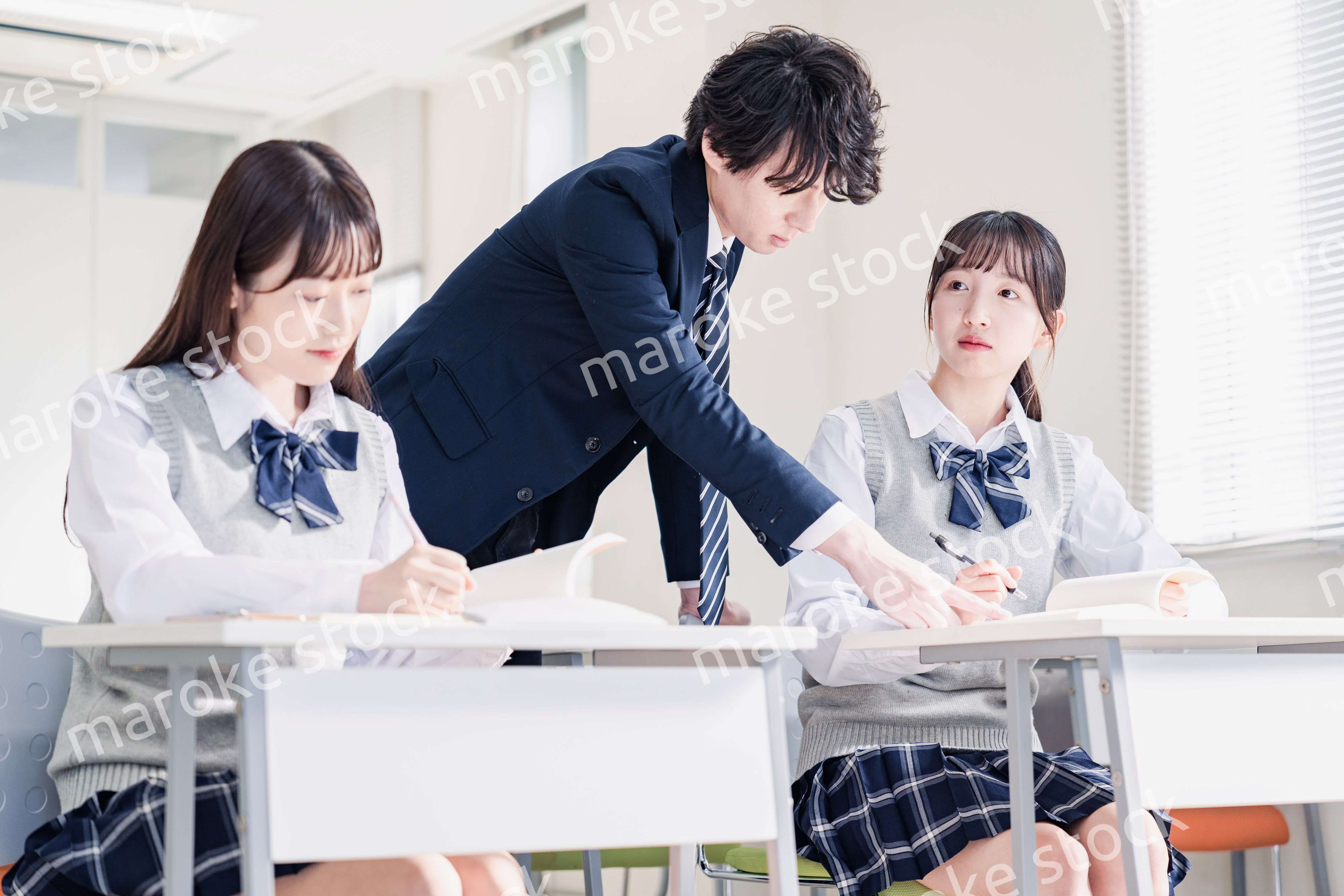 教室で先生に質問をする高校生