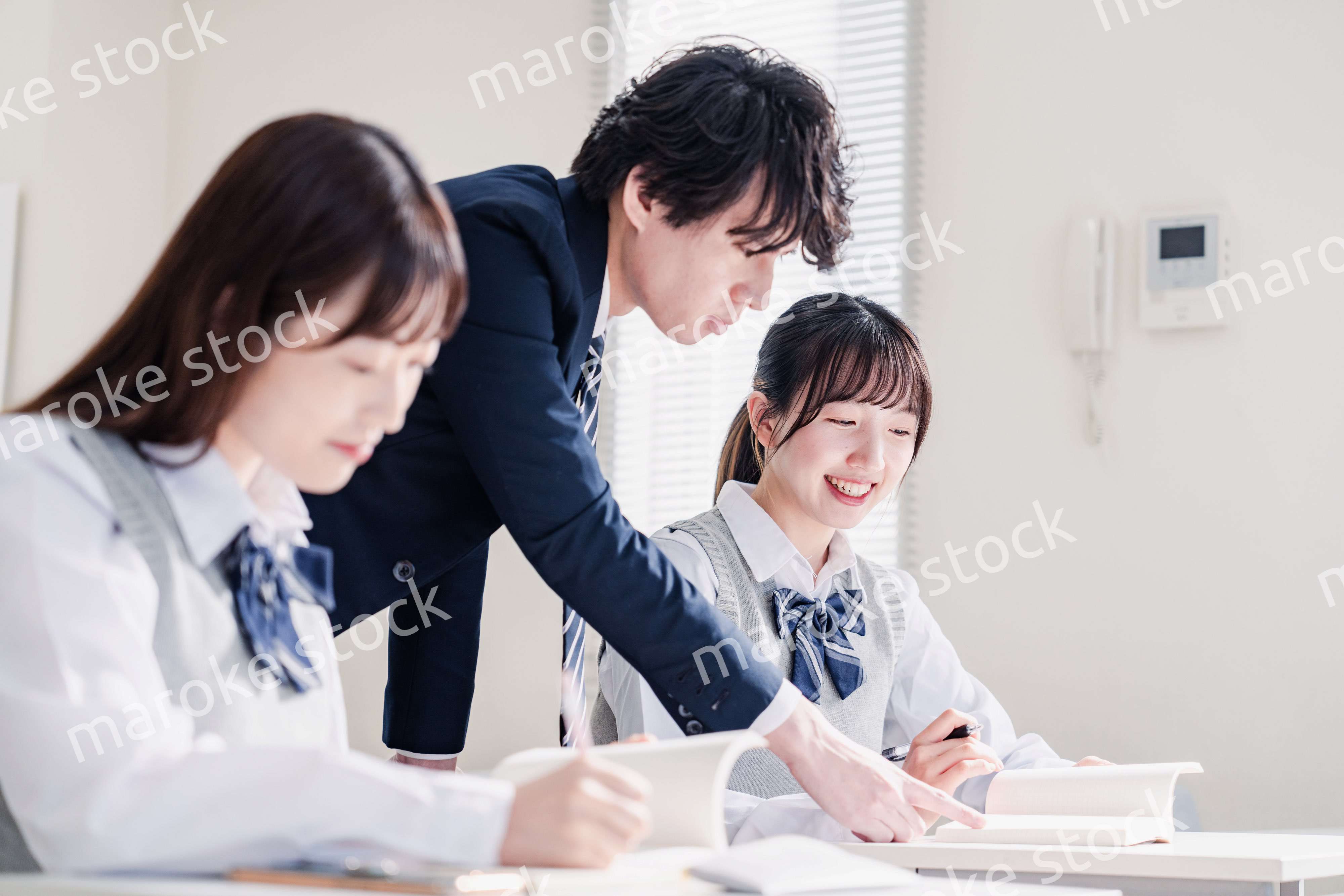 教室で先生に質問をする高校生