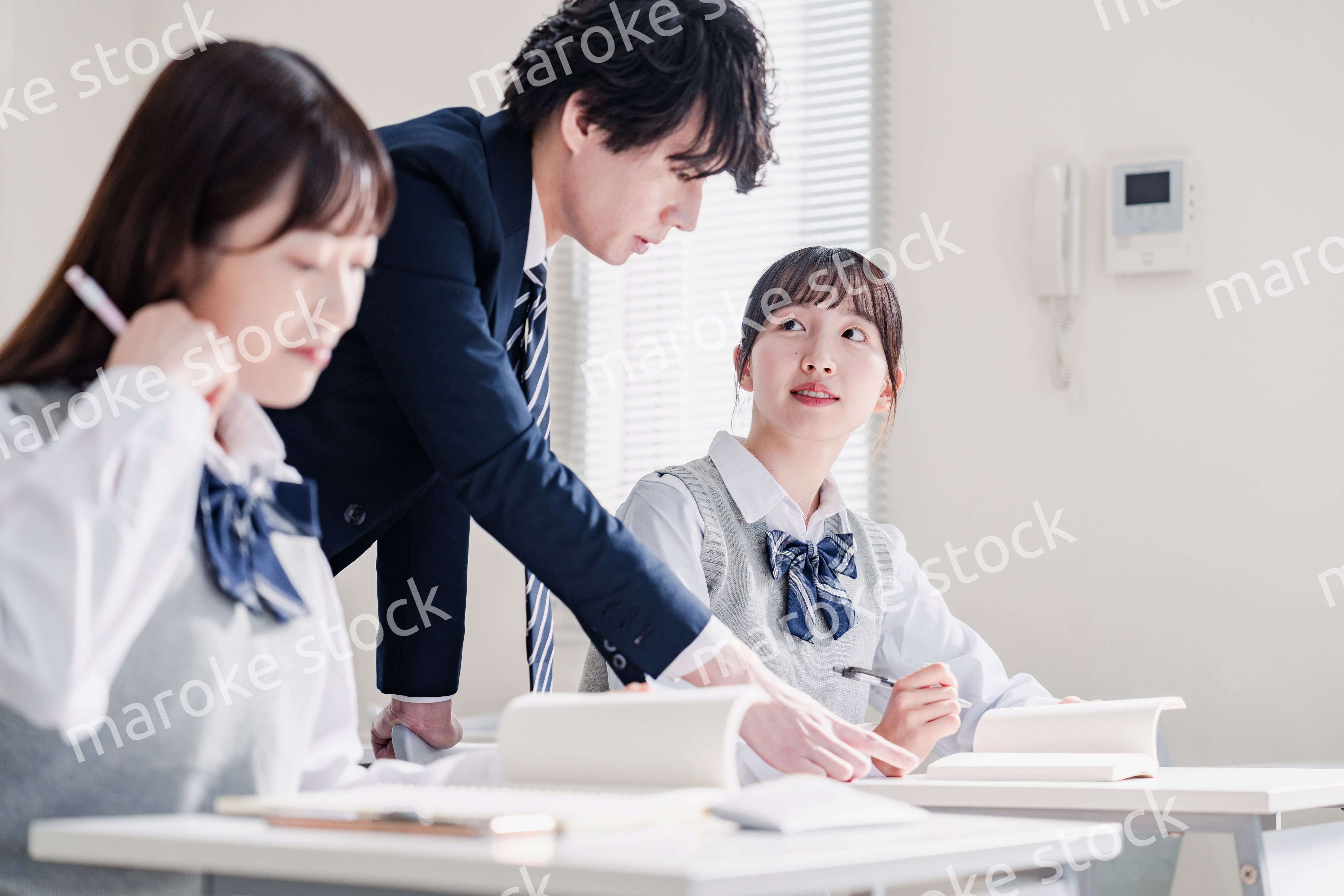 教室で先生に質問をする高校生