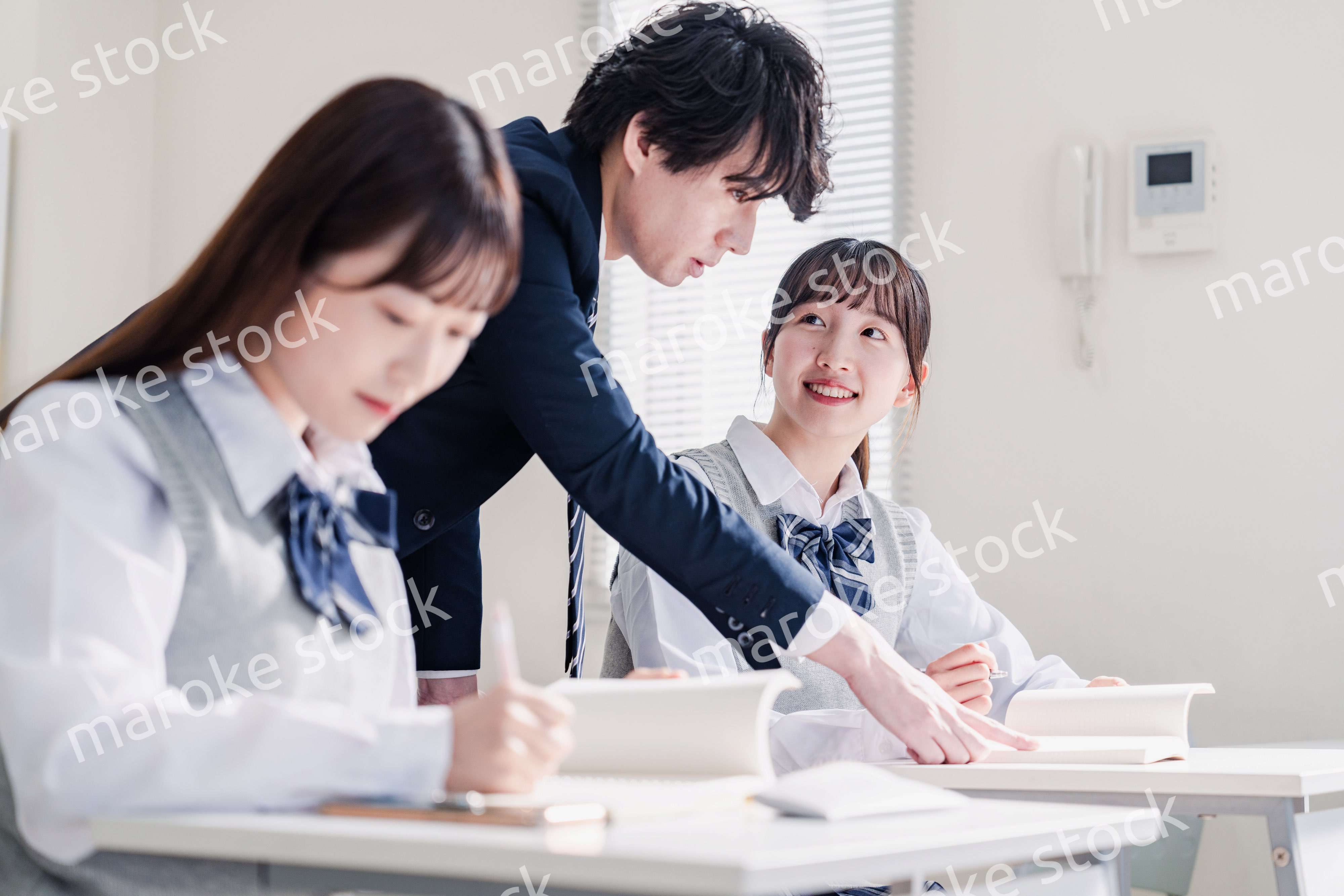 教室で先生に質問をする高校生