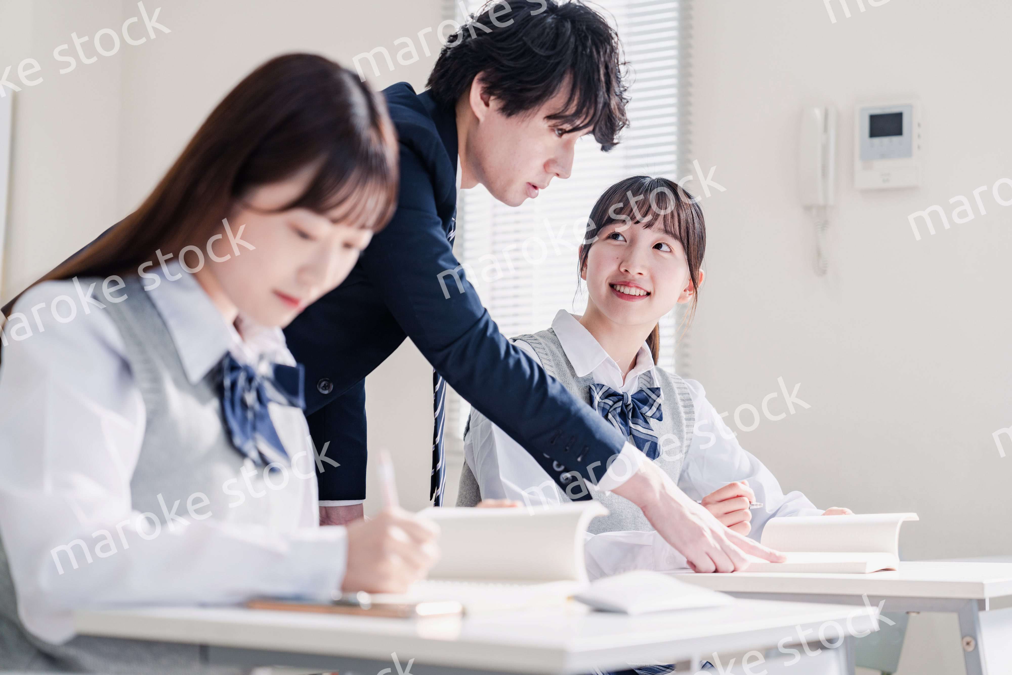 教室で先生に質問をする高校生