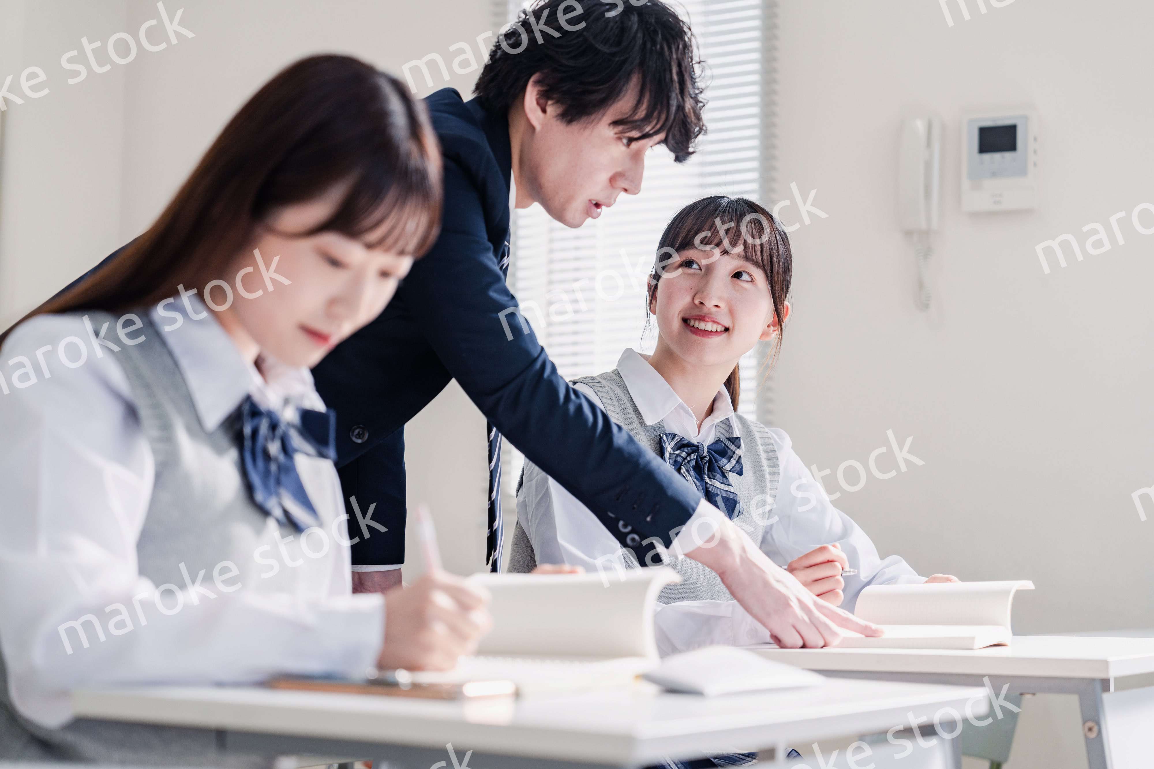 教室で先生に質問をする高校生