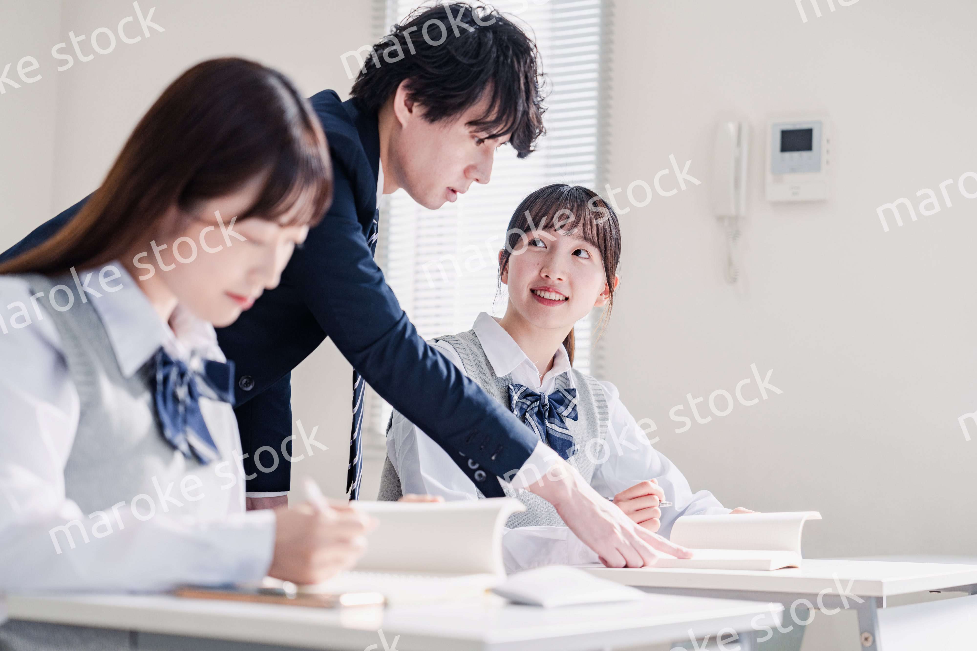 教室で先生に質問をする高校生