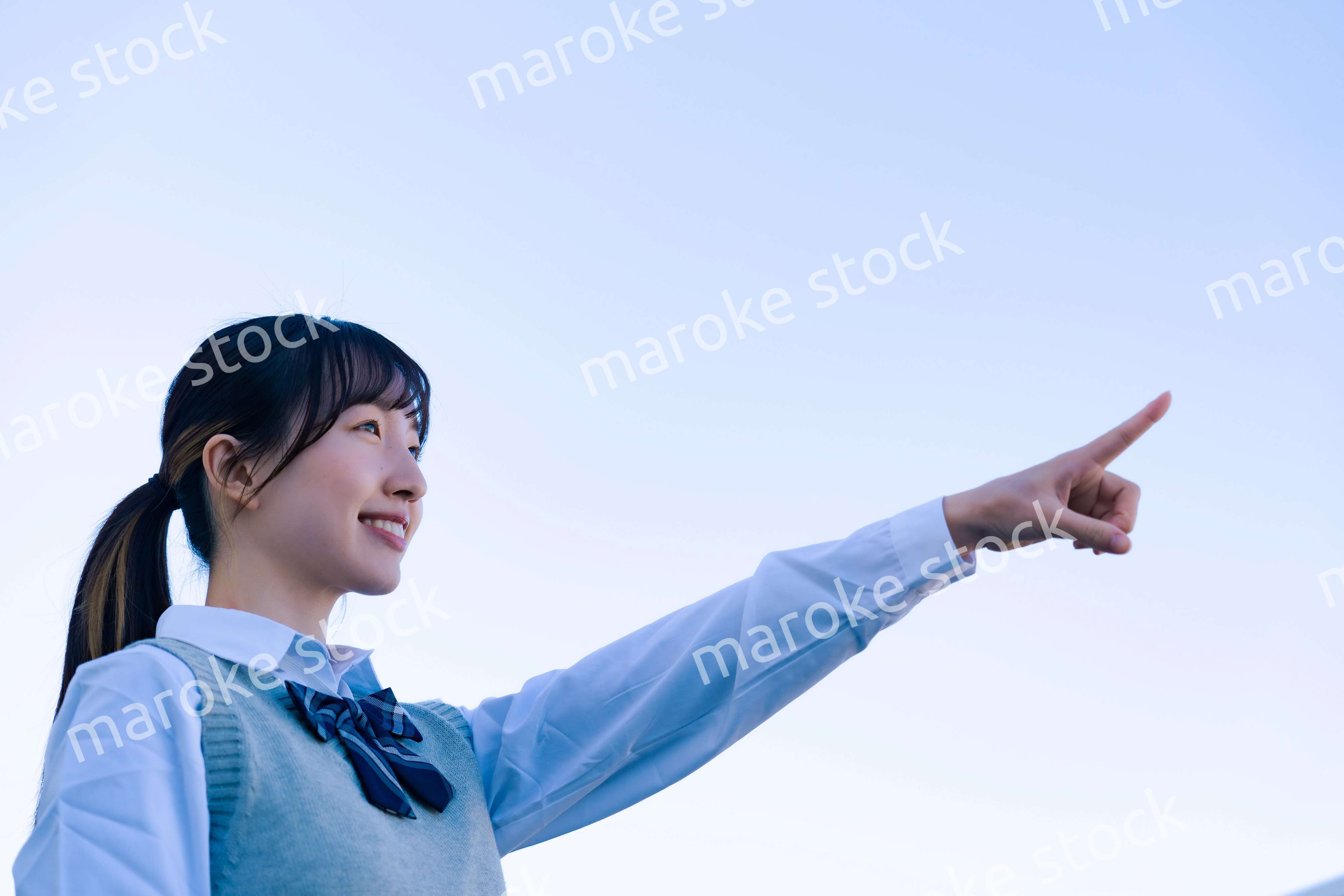 制服で上を指差す女子高生
