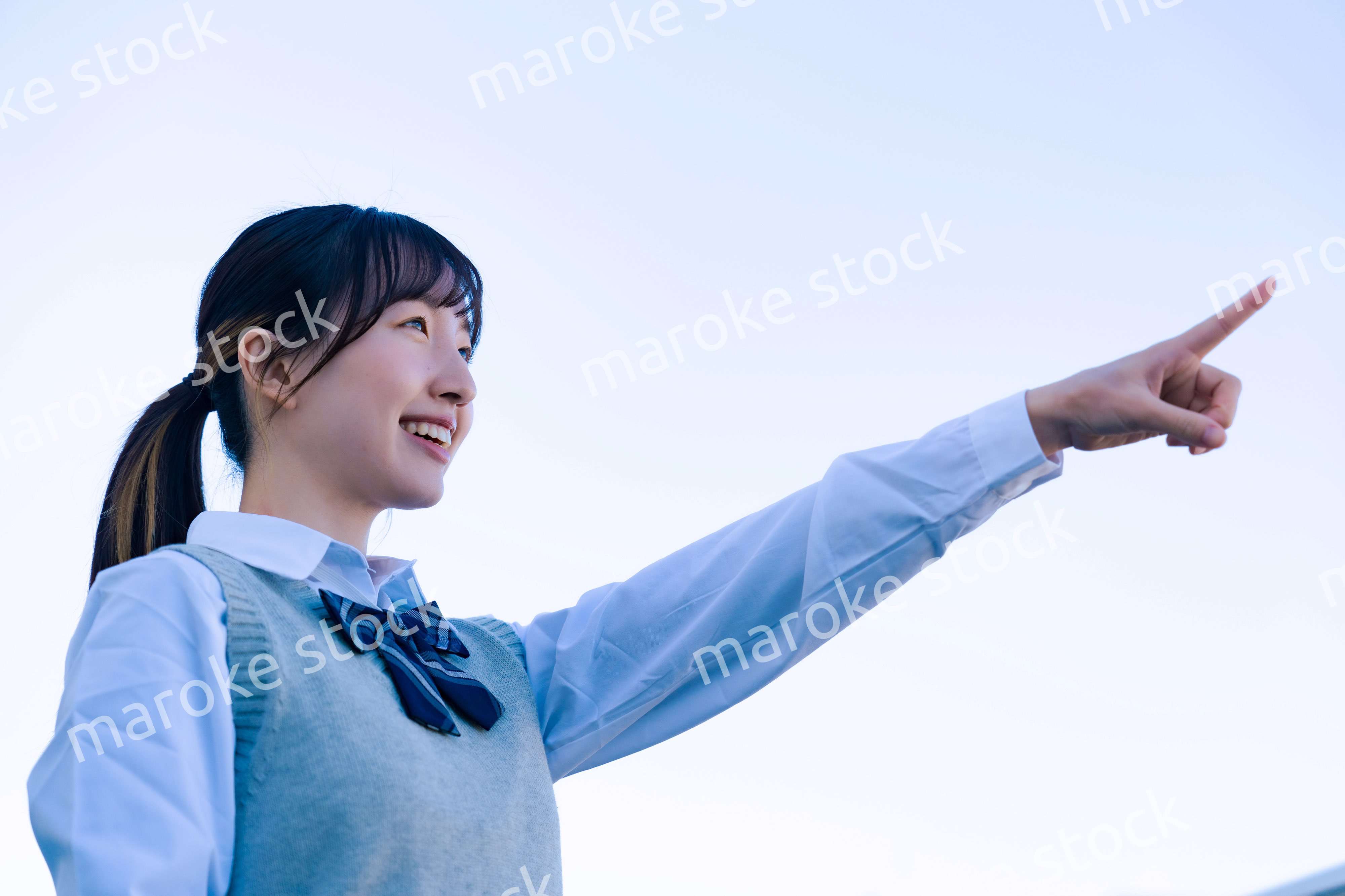 制服で上を指差す女子高生