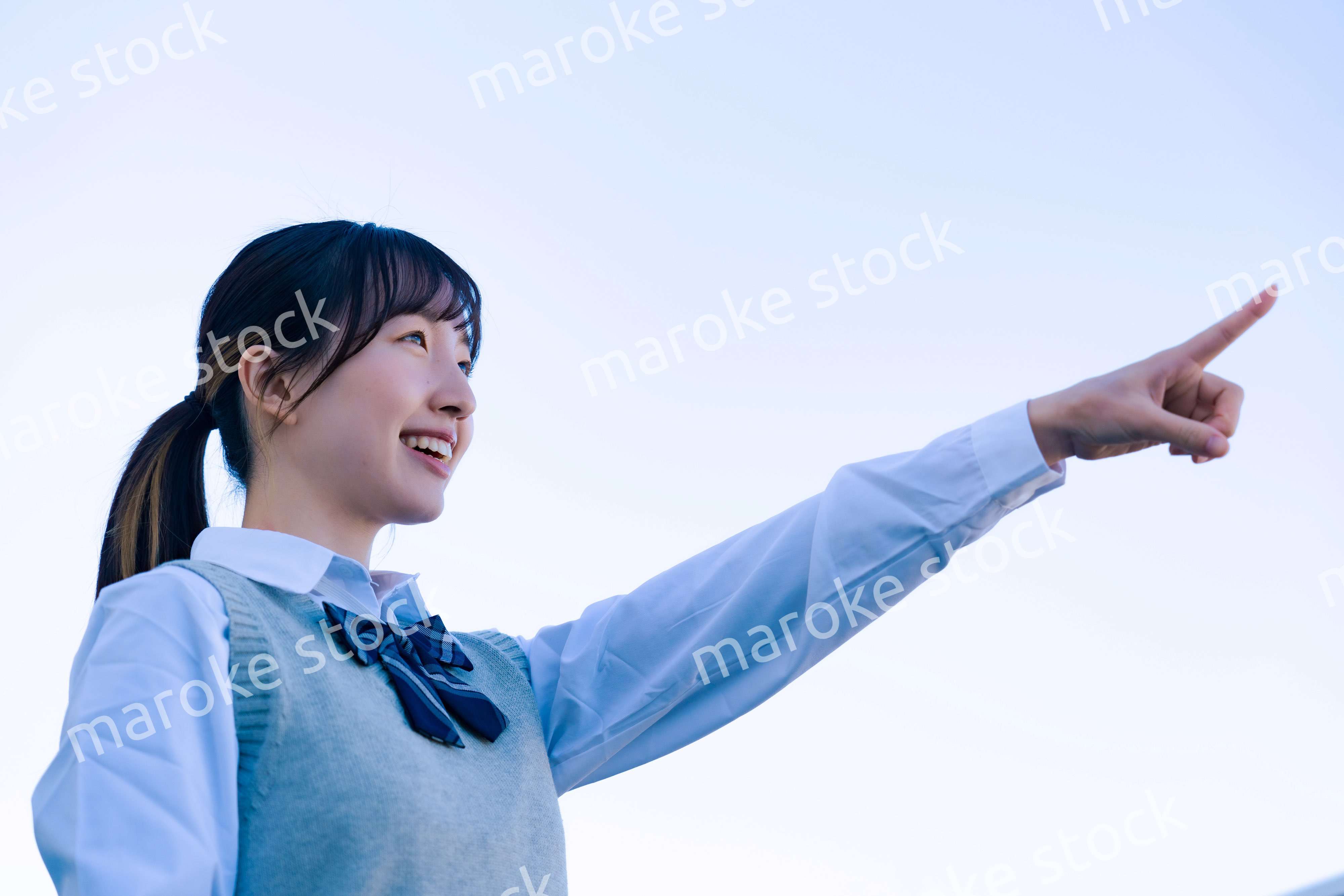 制服で上を指差す女子高生