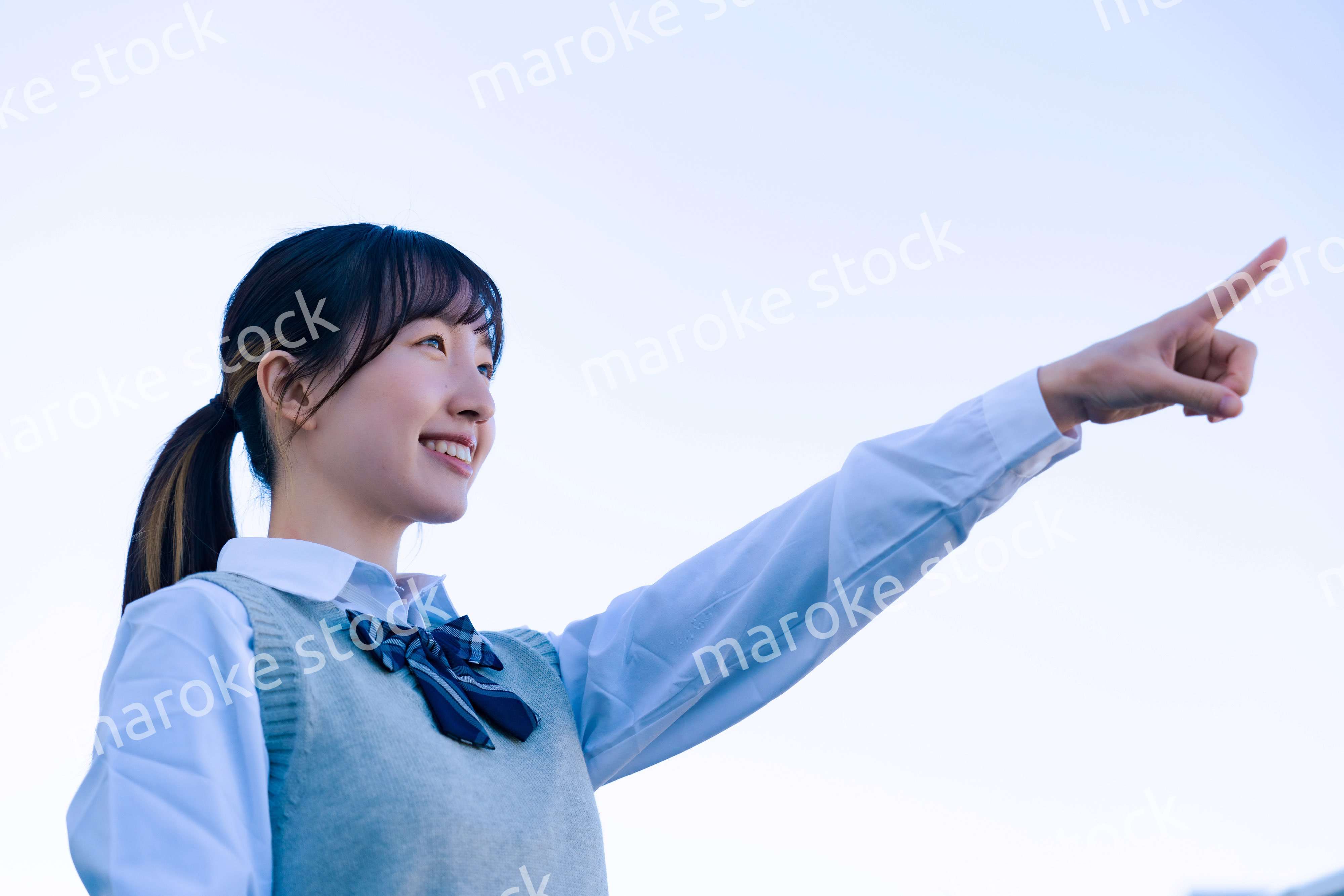 制服で上を指差す女子高生
