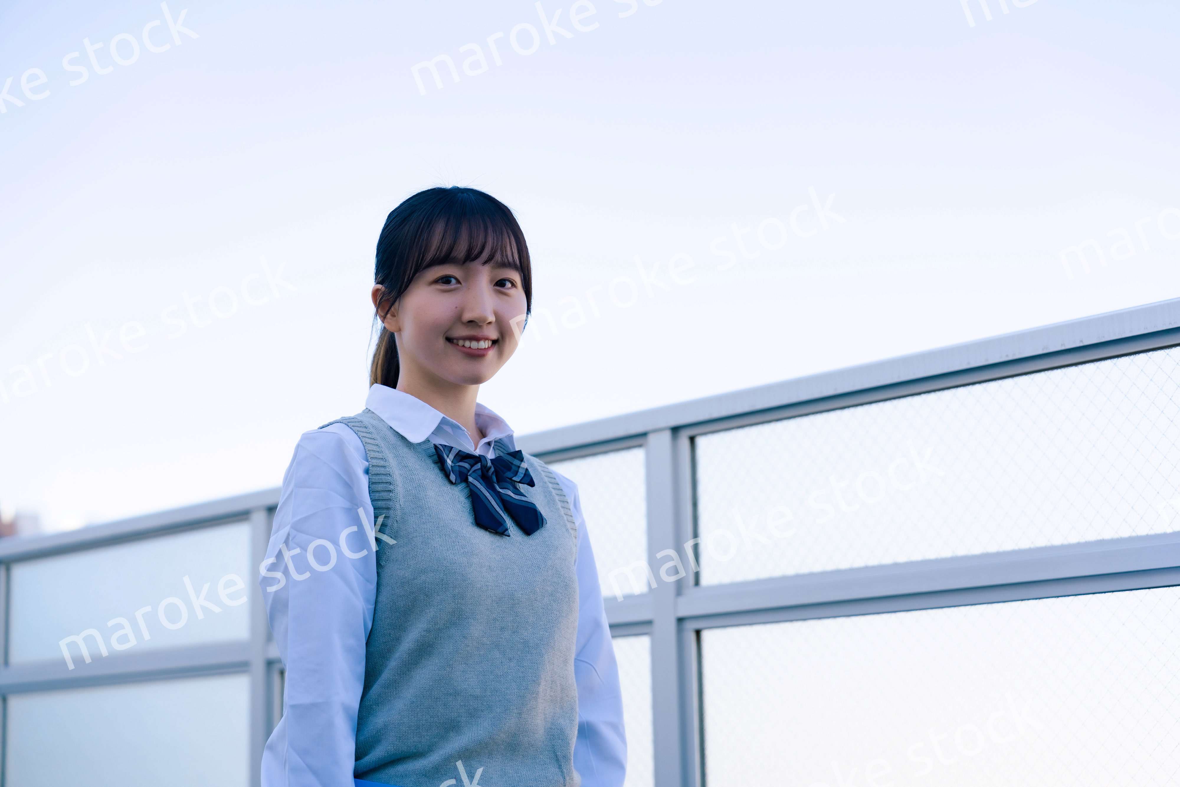 学校の屋上を歩く女子高生