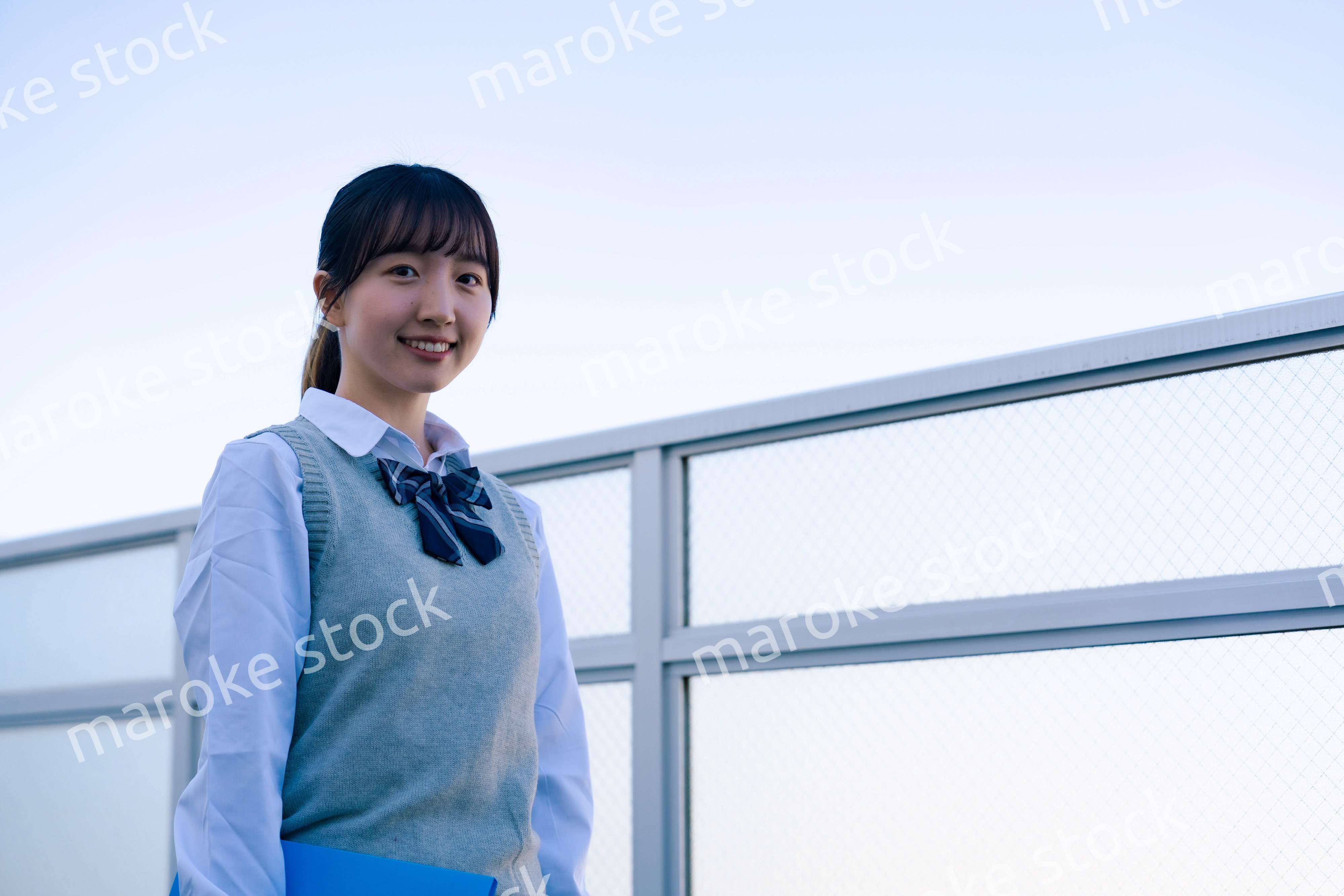 学校の屋上を歩く女子高生
