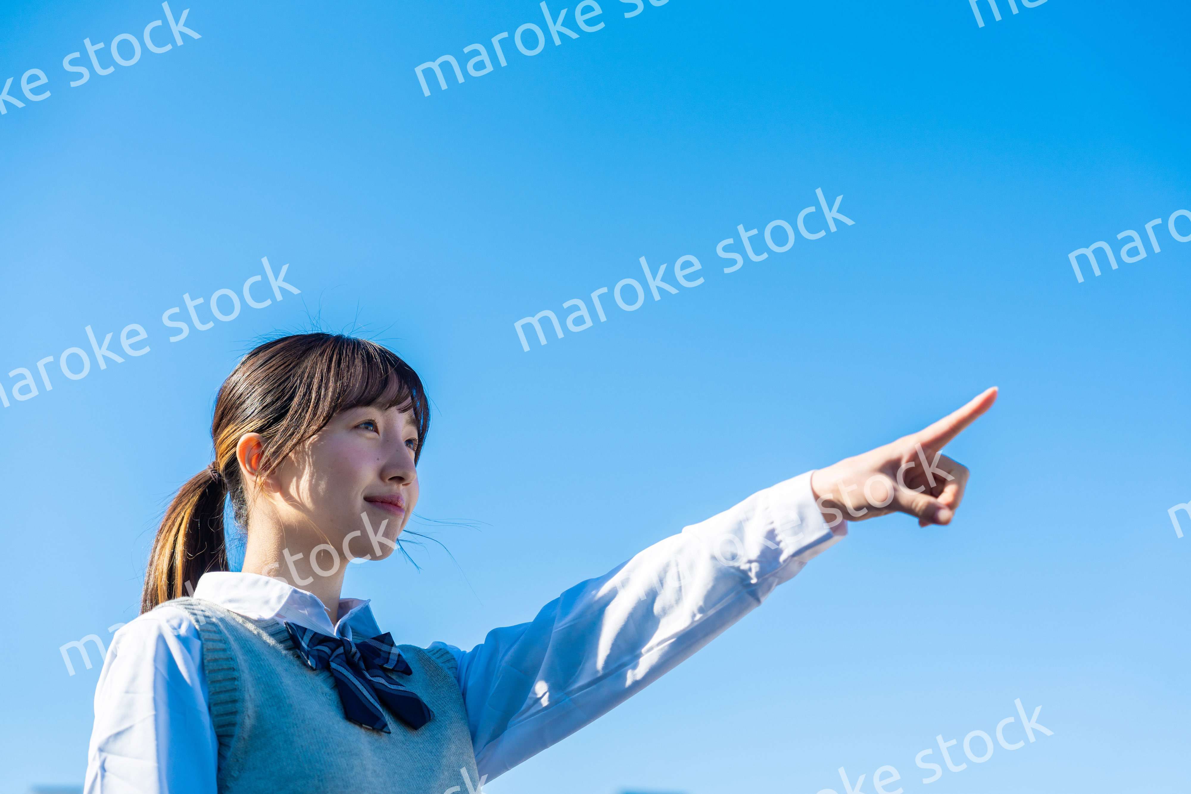制服で上を指差す女子高生