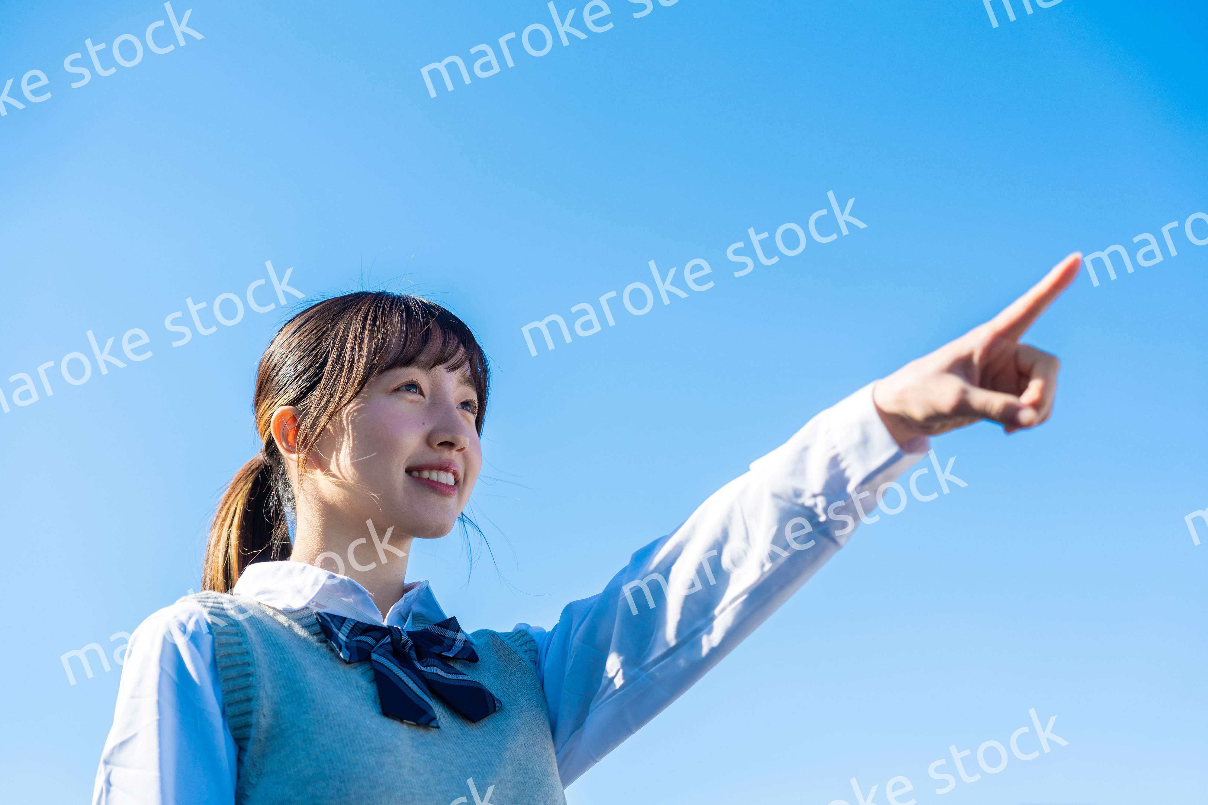 制服で上を指差す女子高生
