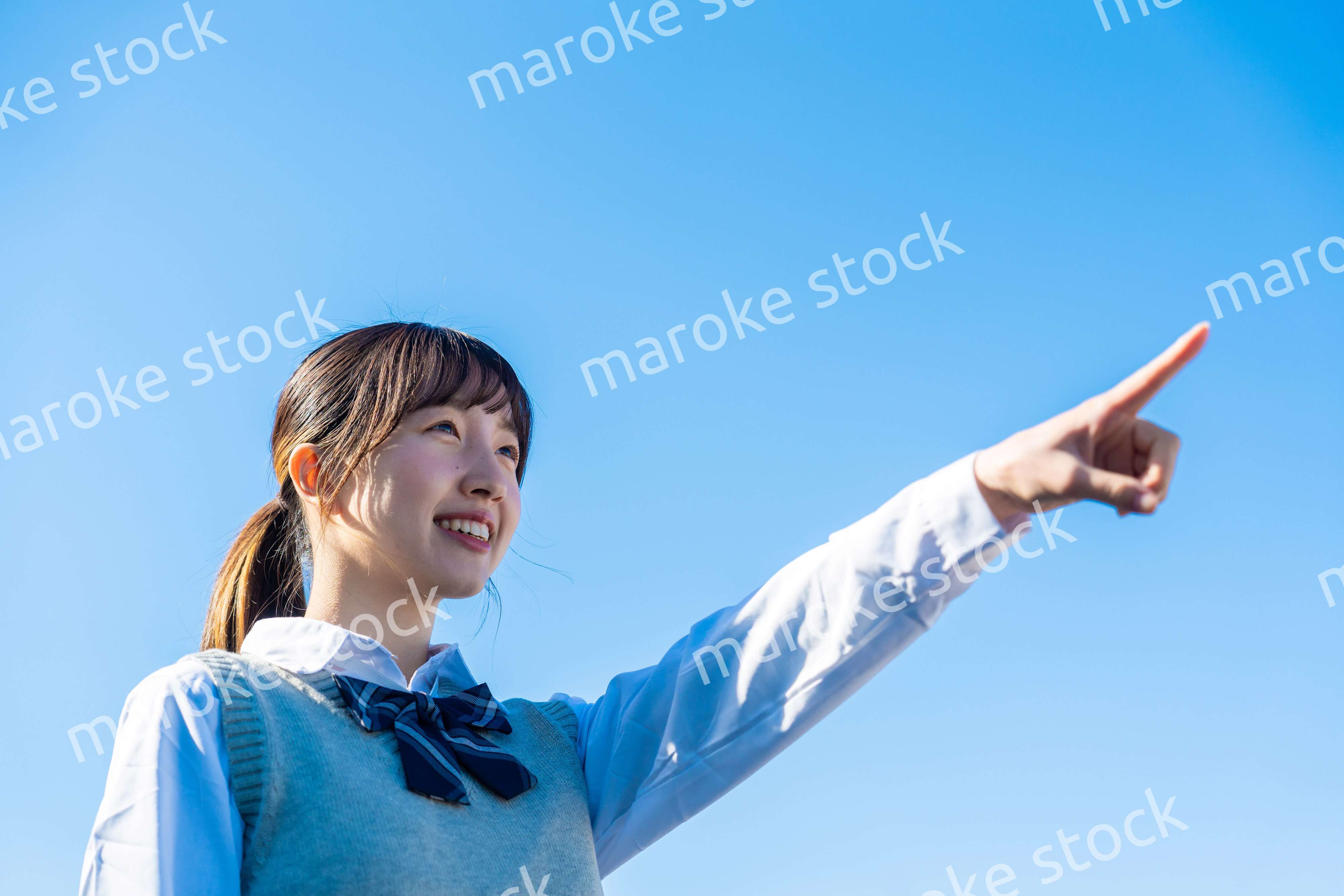 制服で上を指差す女子高生