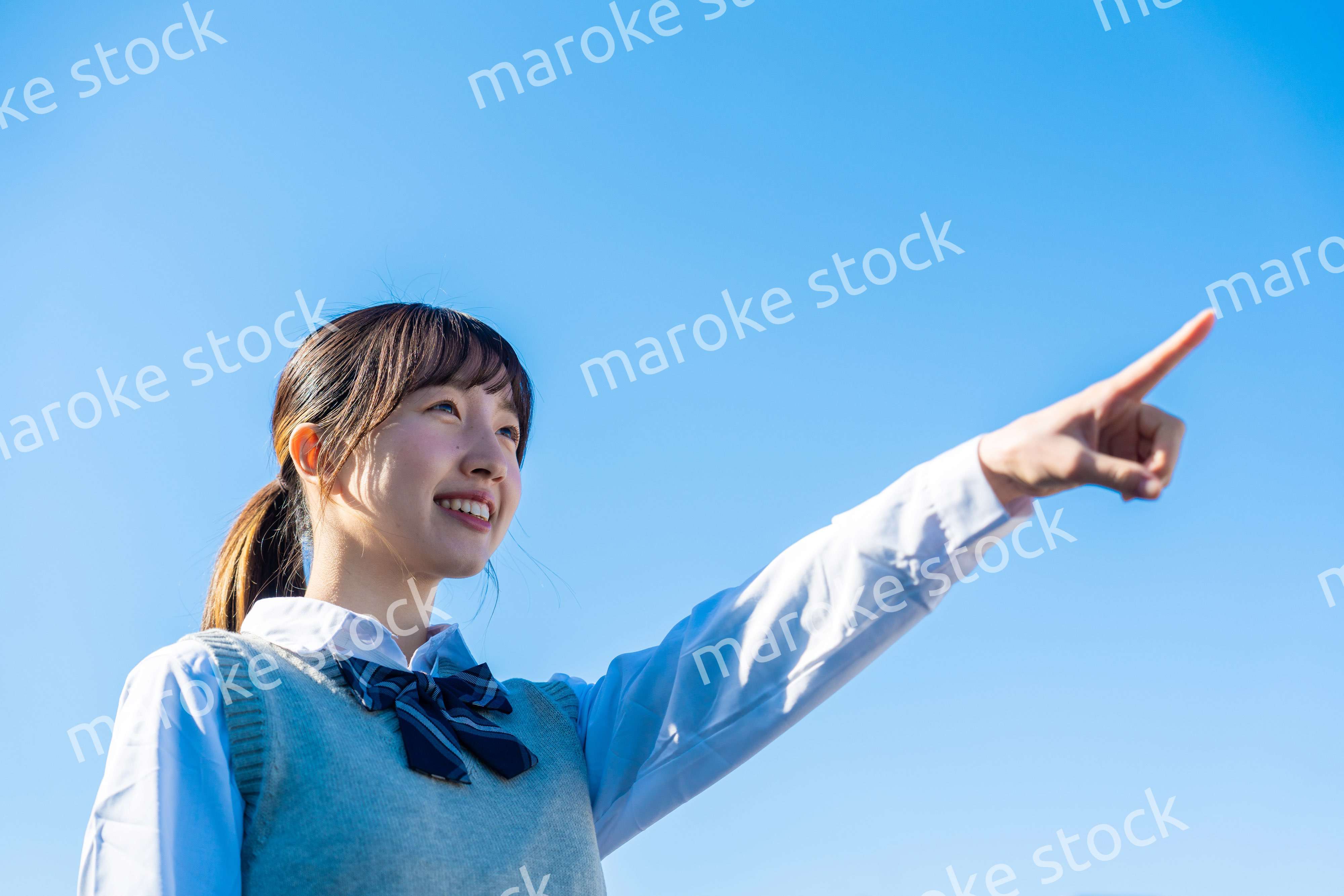 制服で上を指差す女子高生