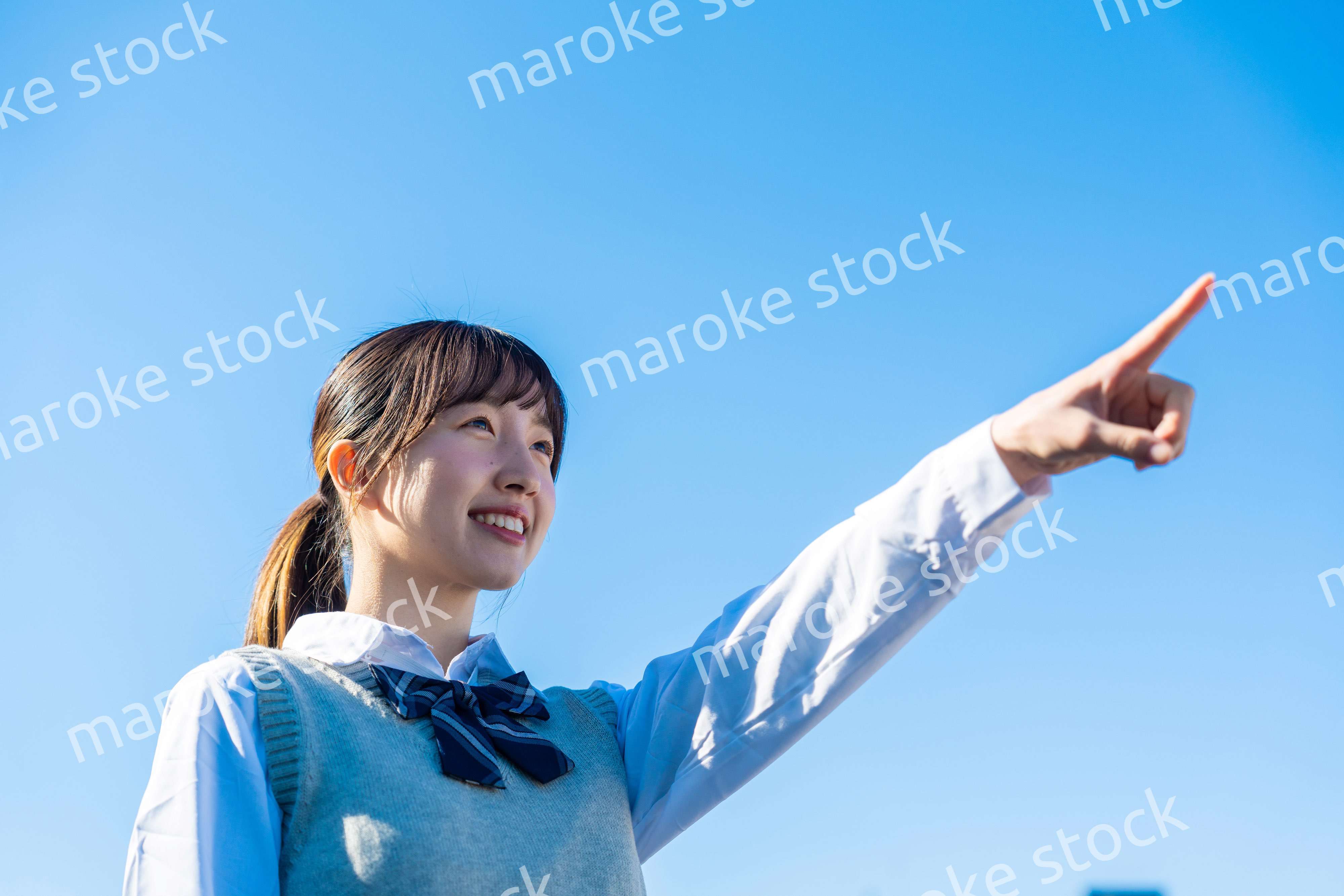 制服で上を指差す女子高生