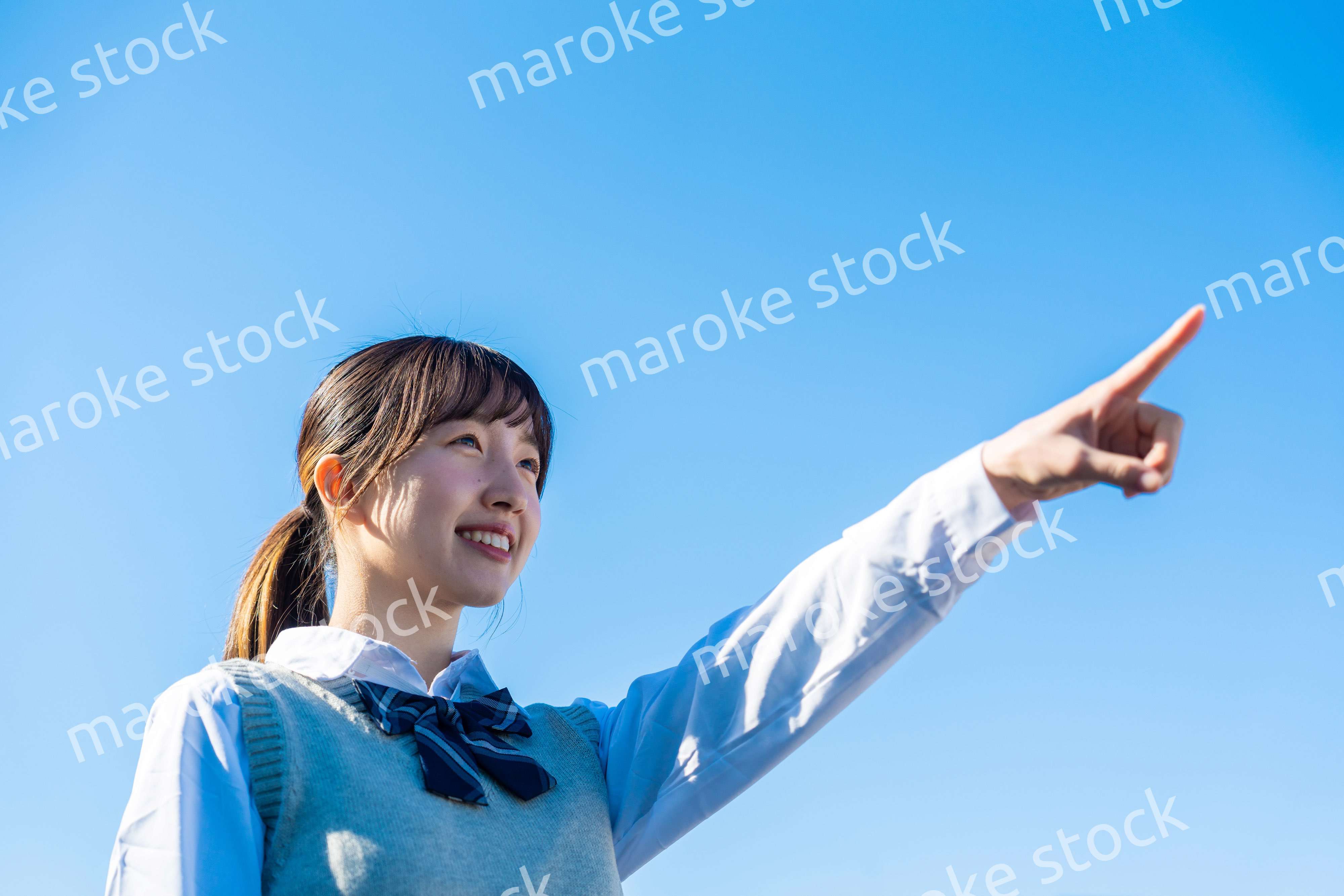 制服で上を指差す女子高生