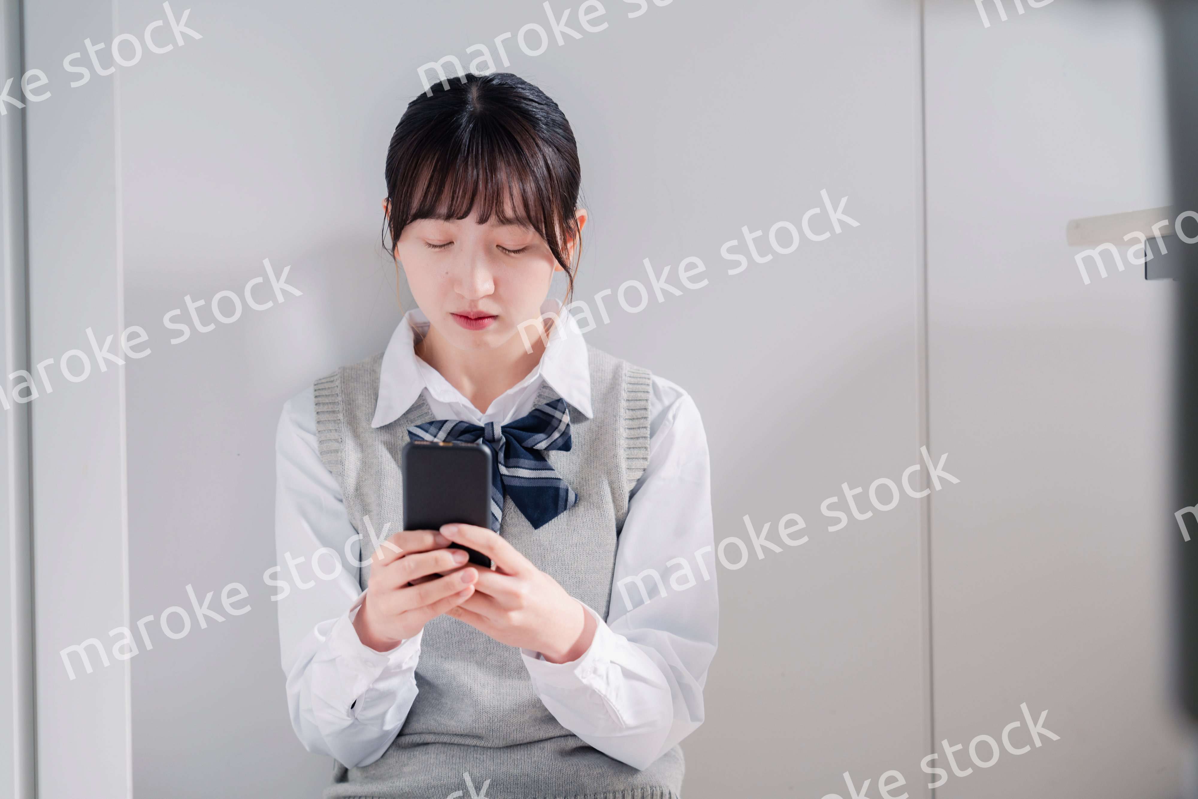 スマホを見ながら落ち込む女子高生