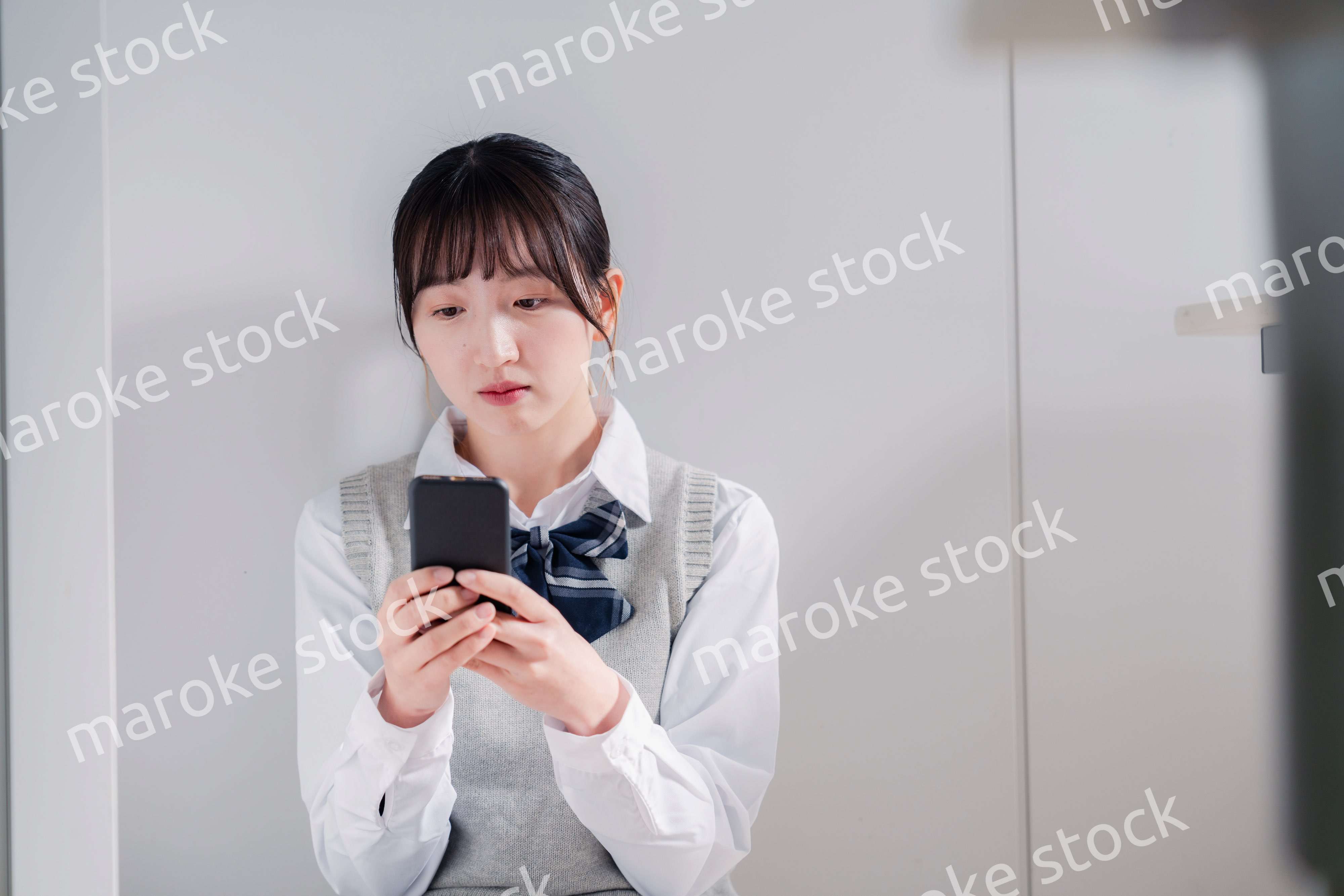 スマホを見ながら落ち込む女子高生