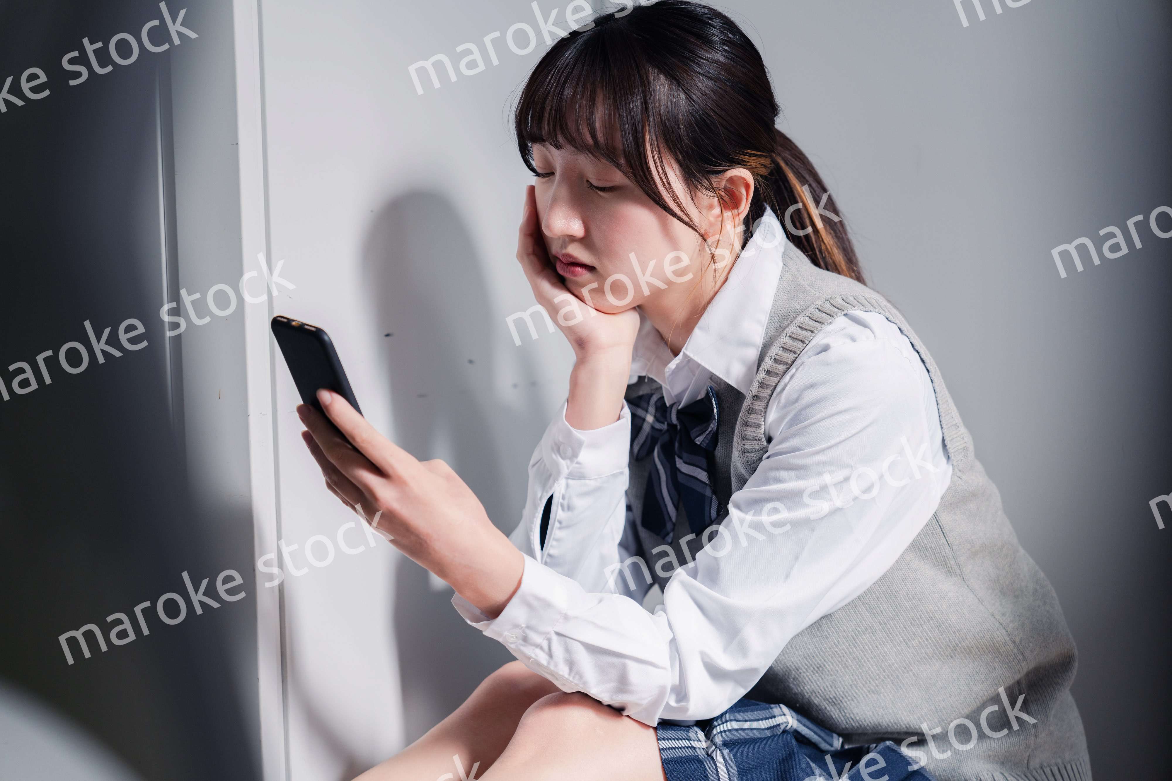 スマホを見ながら落ち込む女子高生