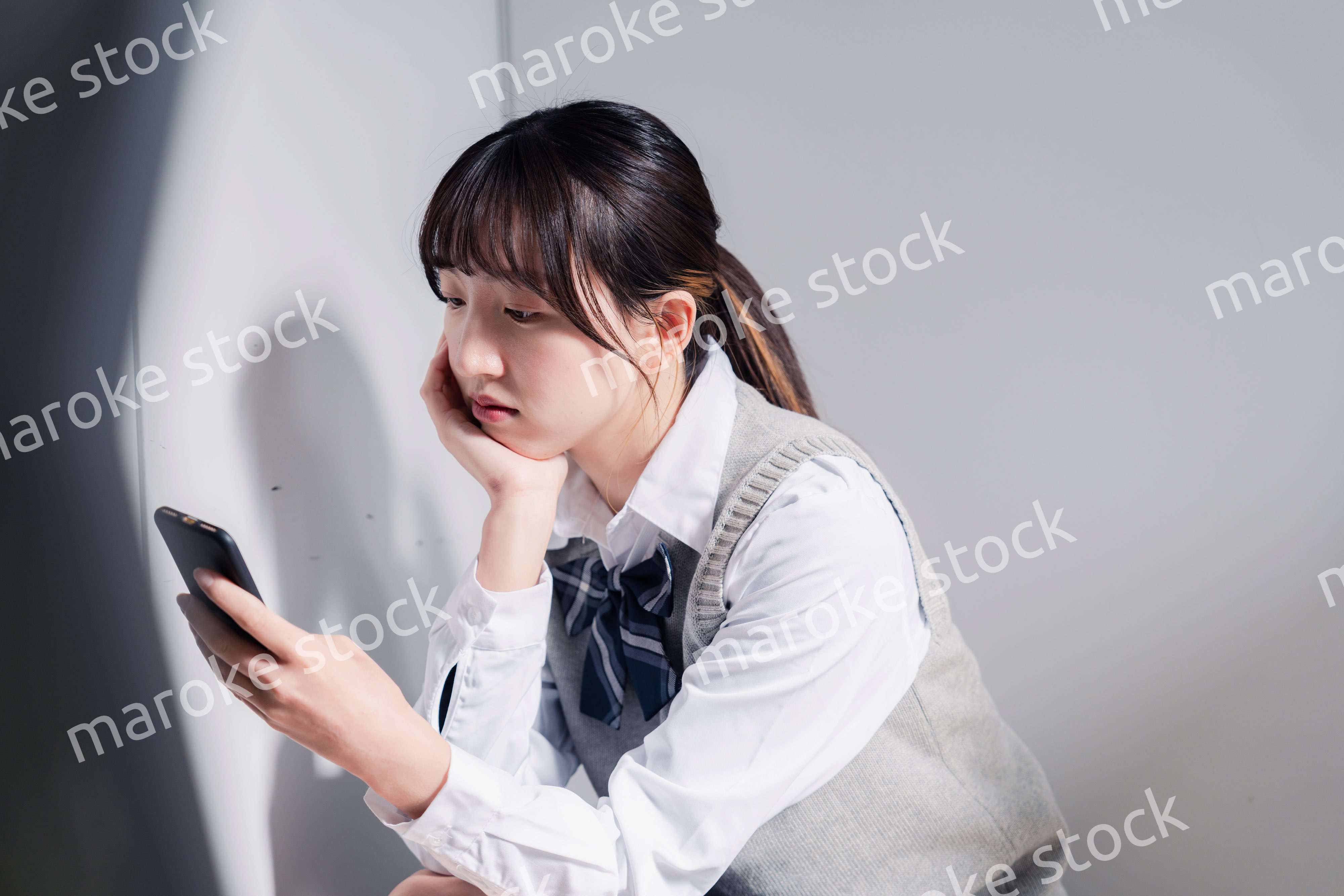 スマホを見ながら落ち込む女子高生