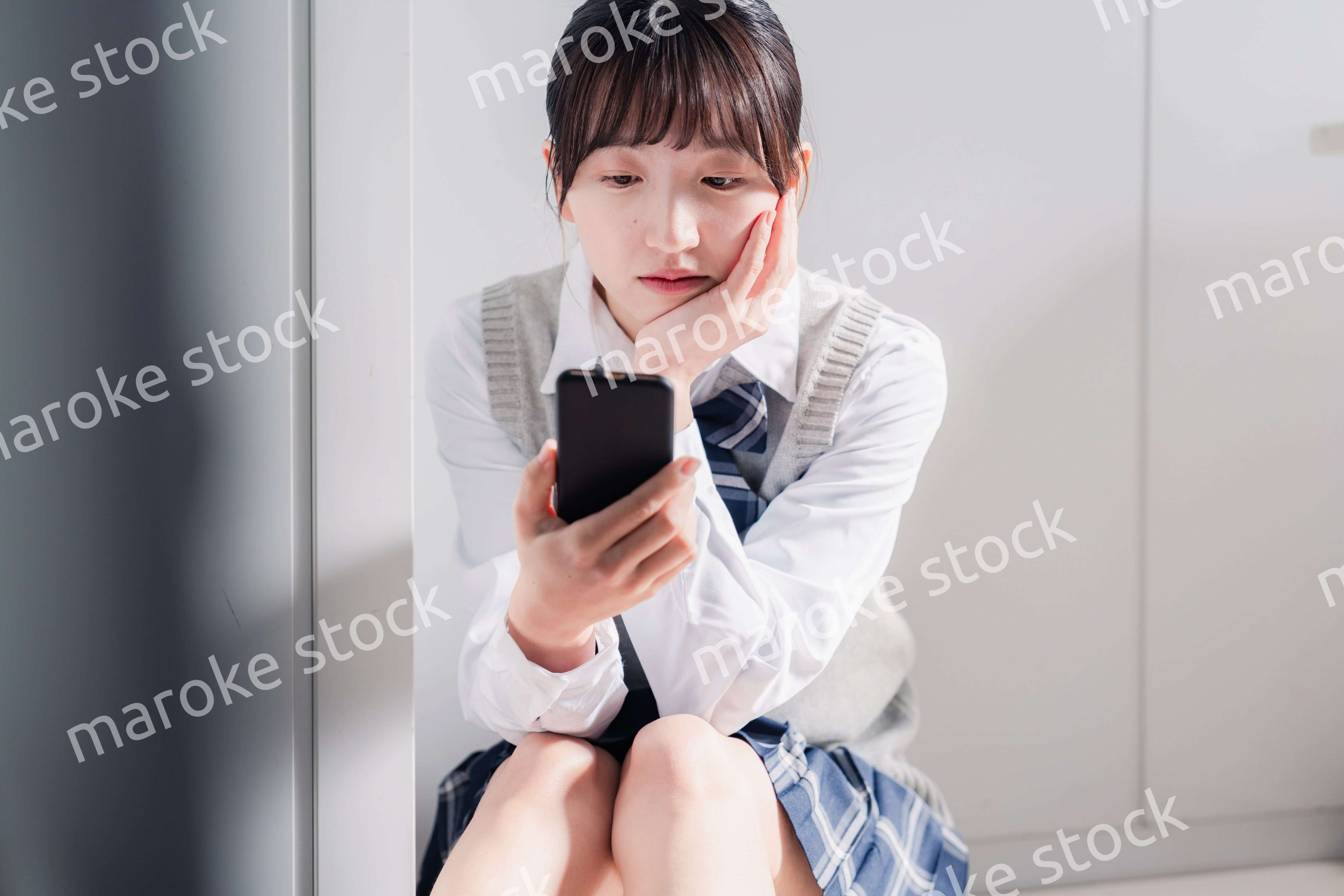 スマホを見ながら落ち込む女子高生