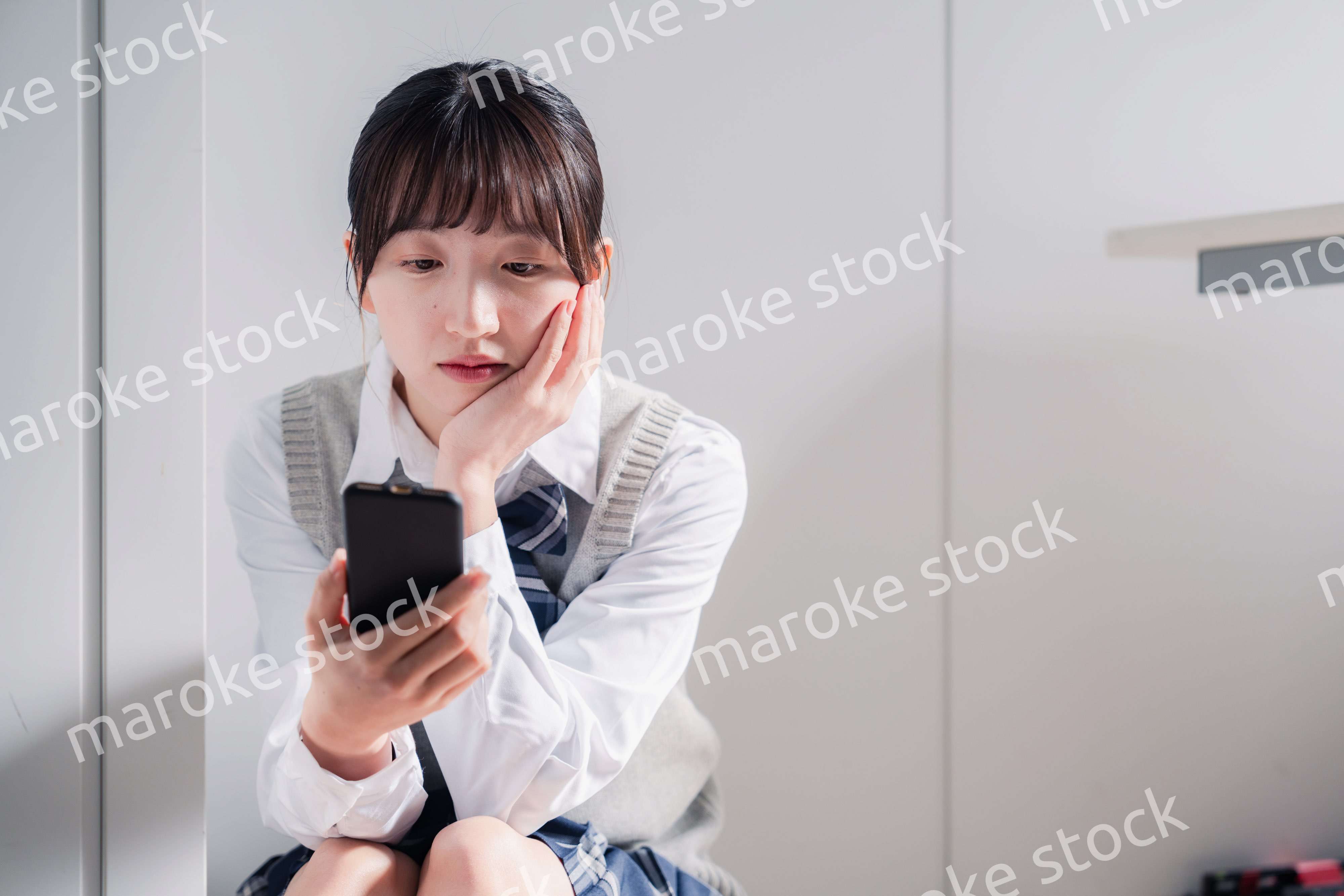 スマホを見ながら落ち込む女子高生
