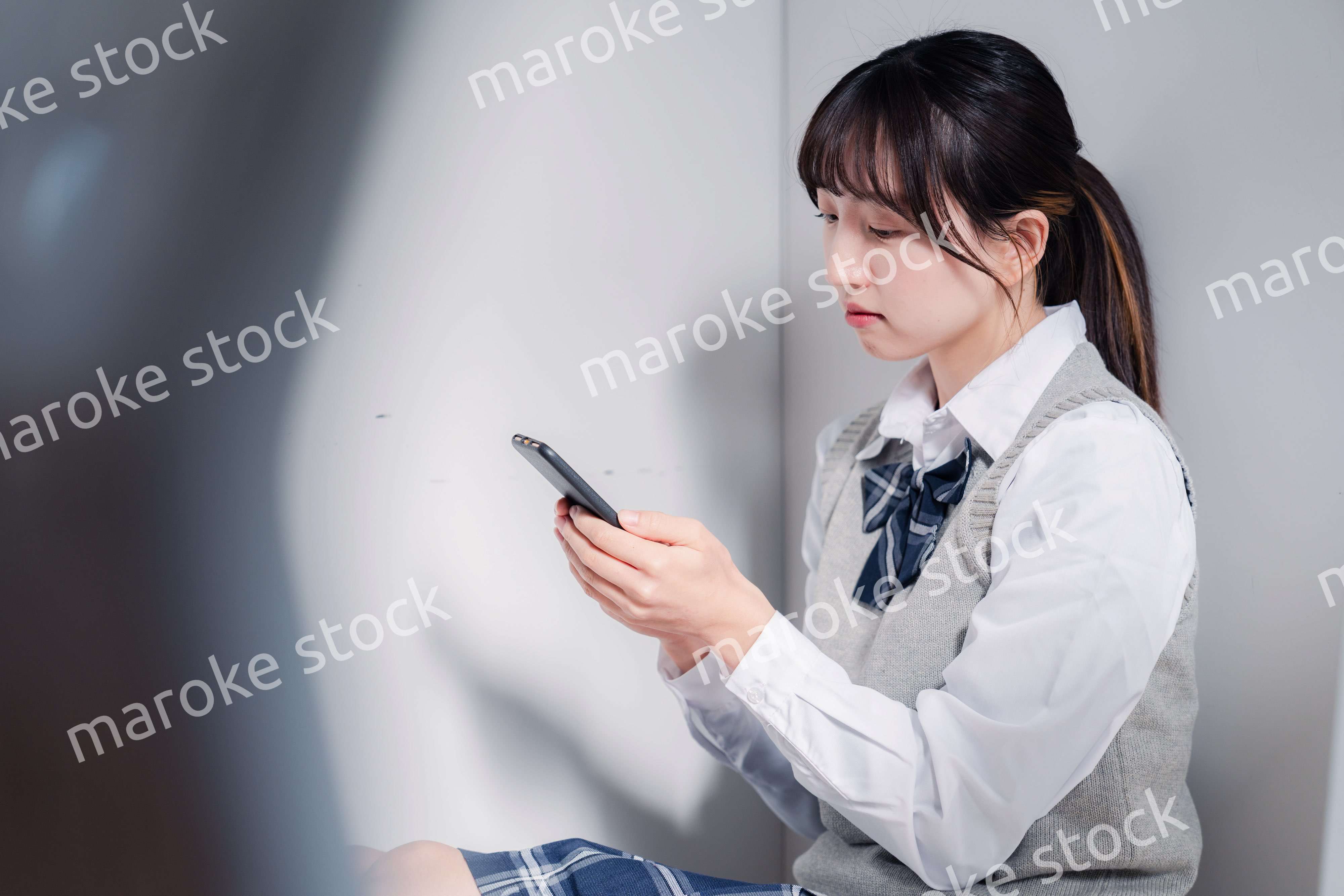 スマホを見ながら落ち込む女子高生