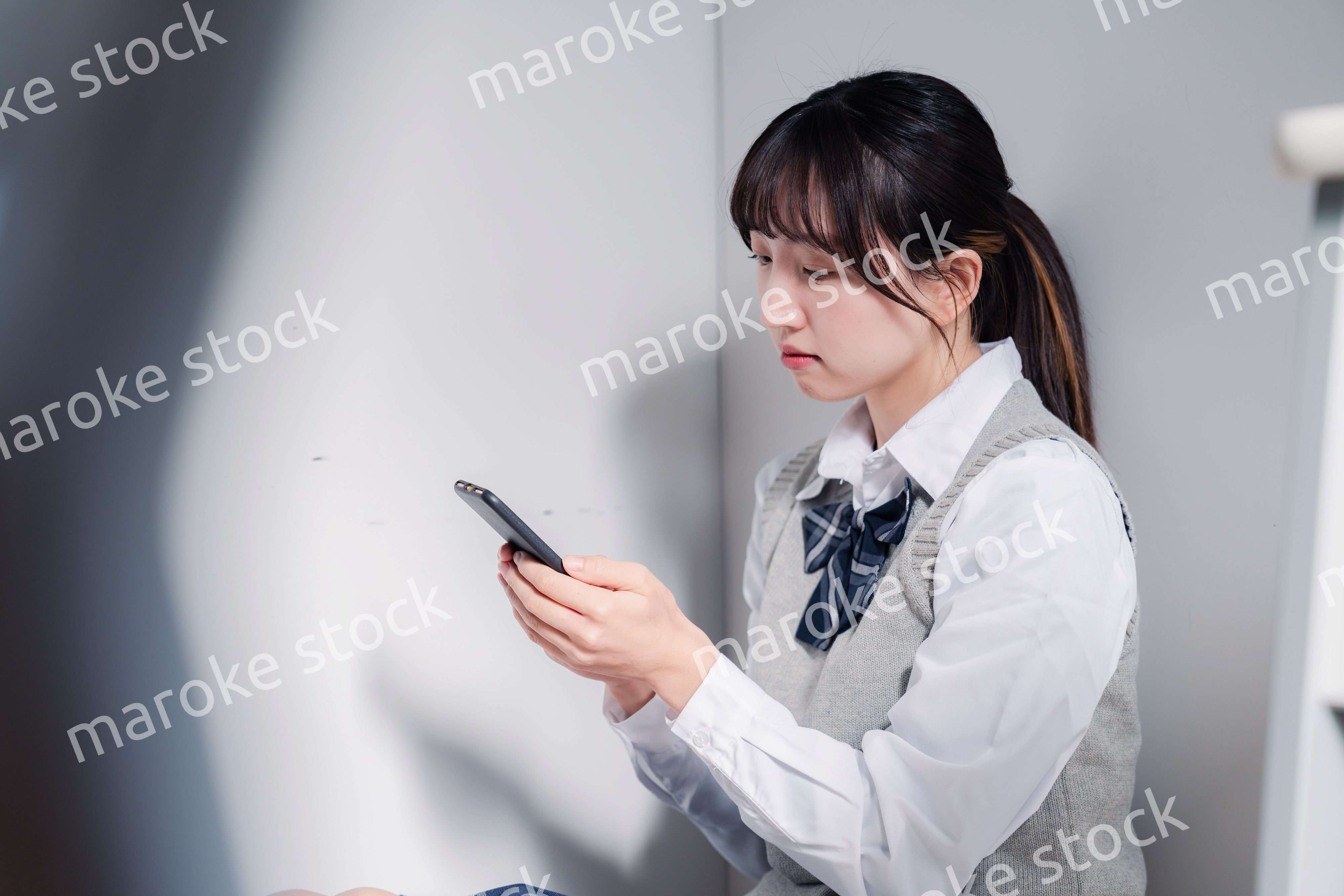 スマホを見ながら落ち込む女子高生