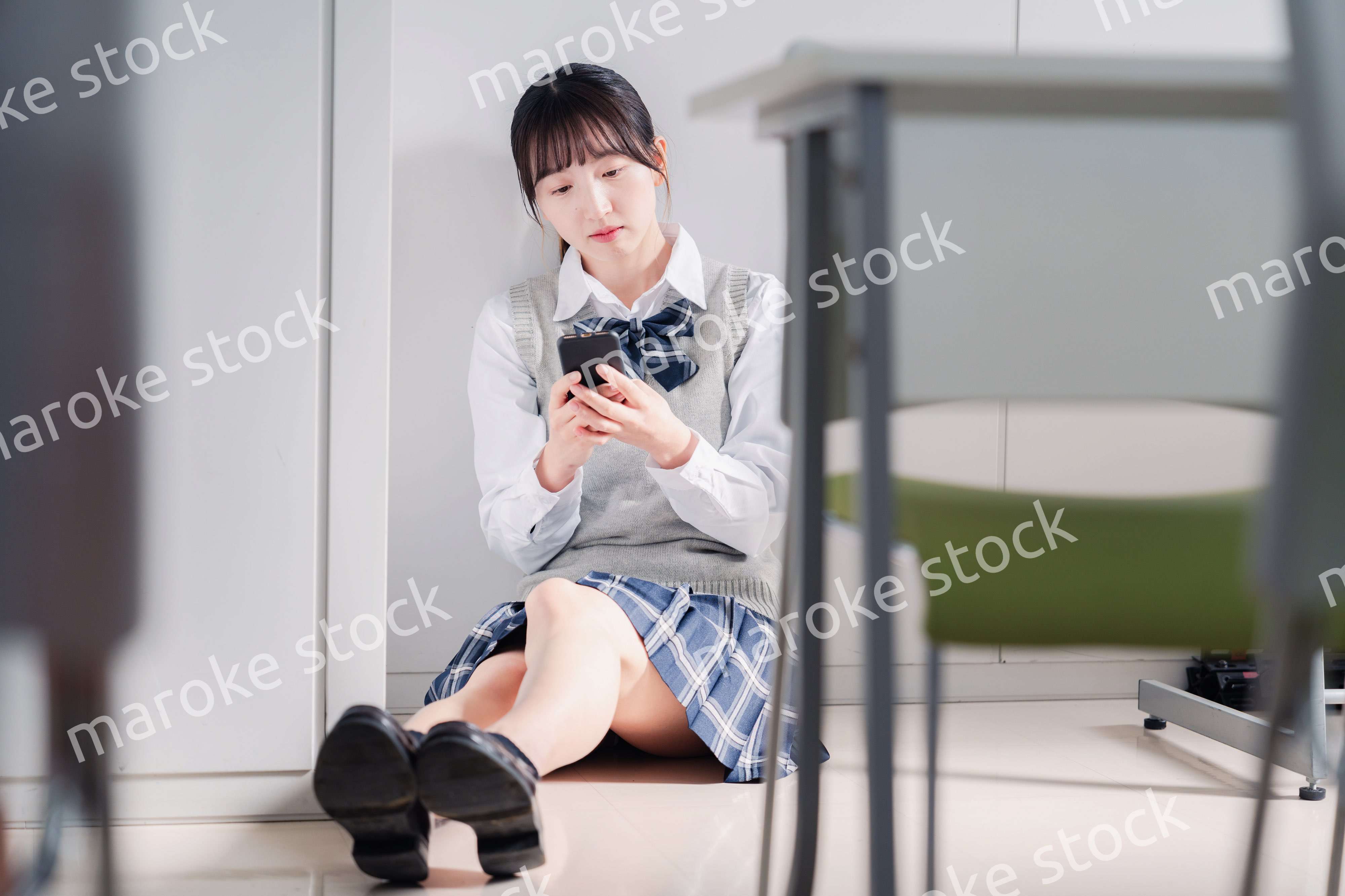 スマホを見ながら落ち込む女子高生