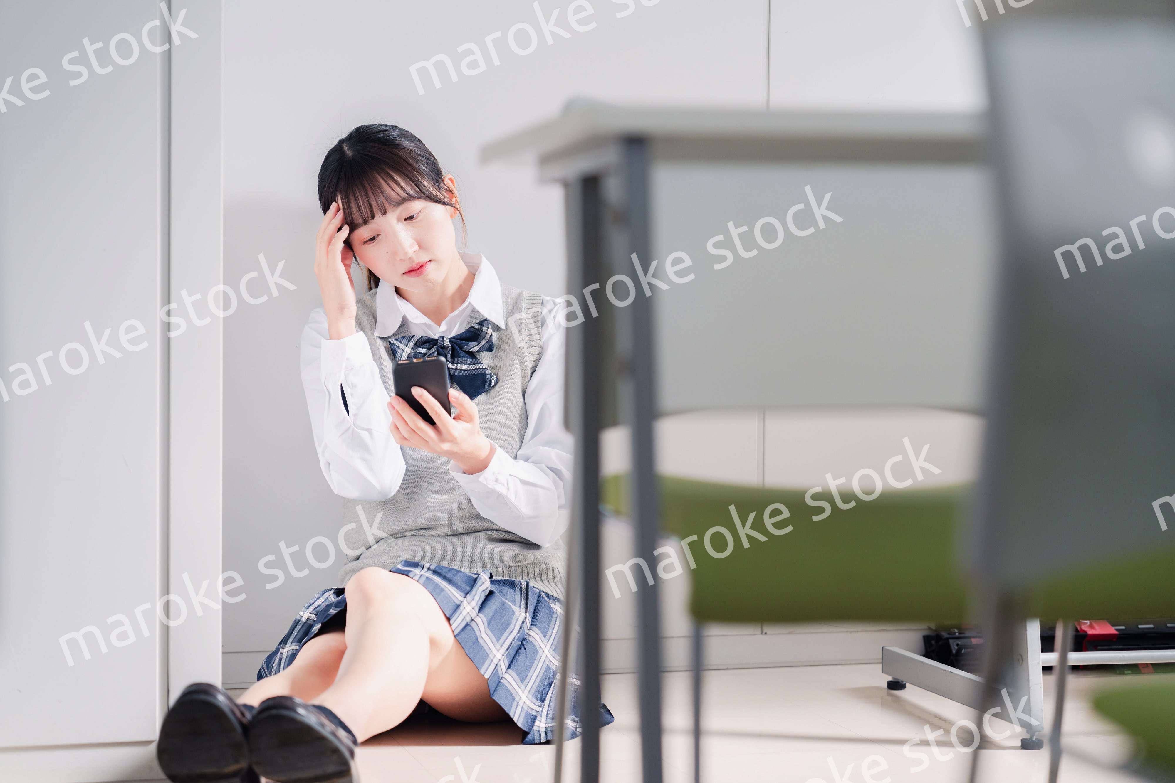 スマホを見ながら落ち込む女子高生