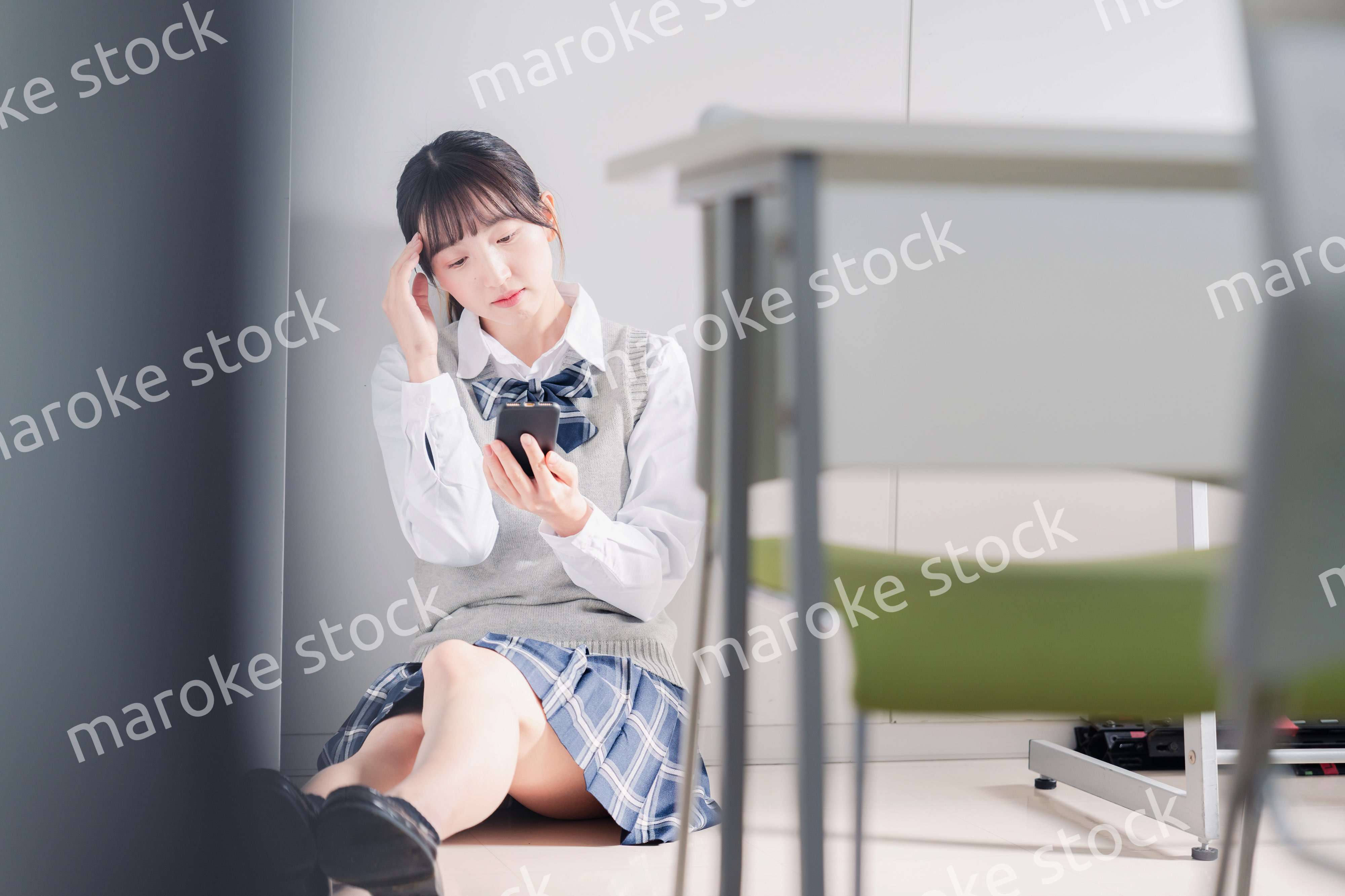 スマホを見ながら落ち込む女子高生