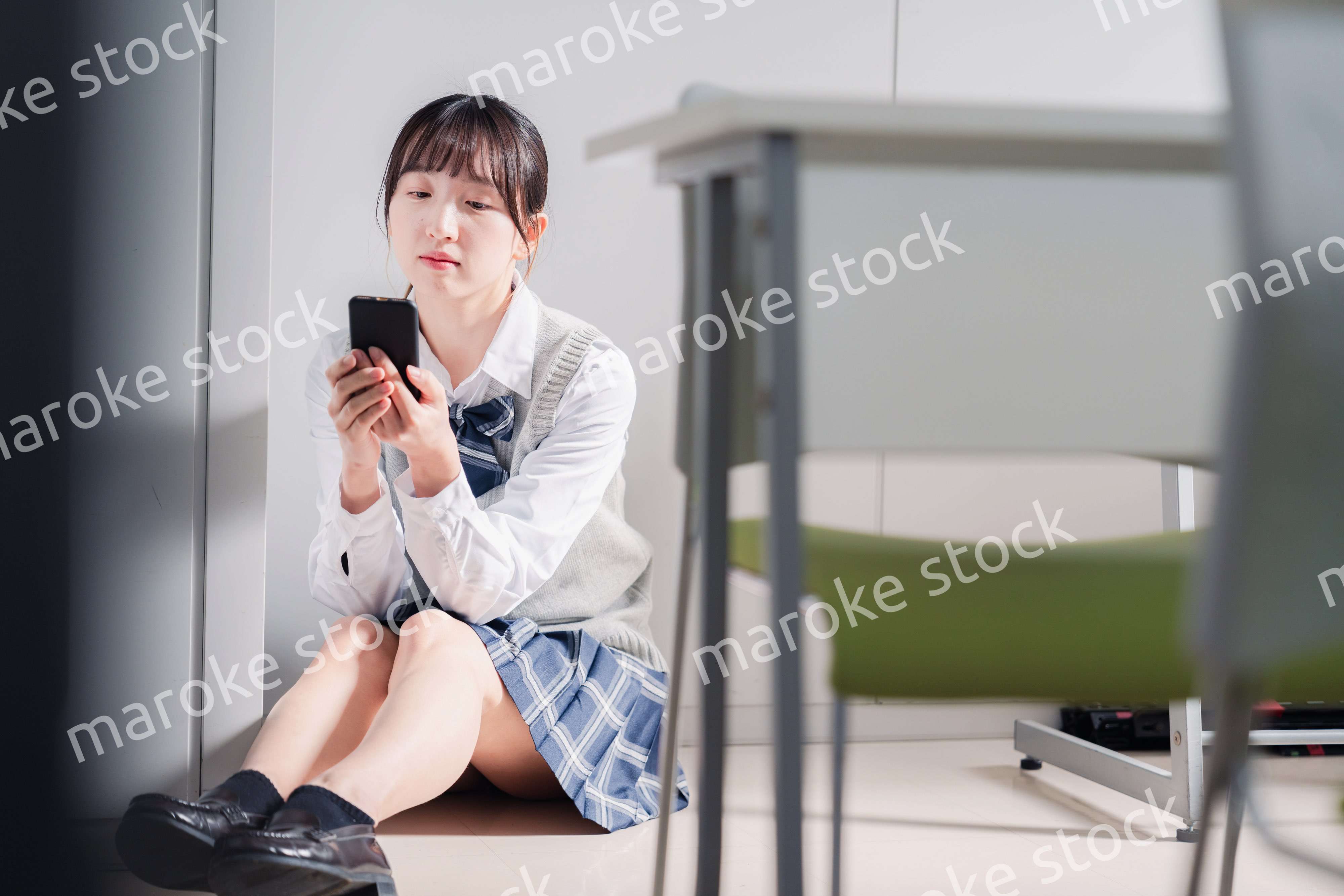 スマホを見ながら落ち込む女子高生