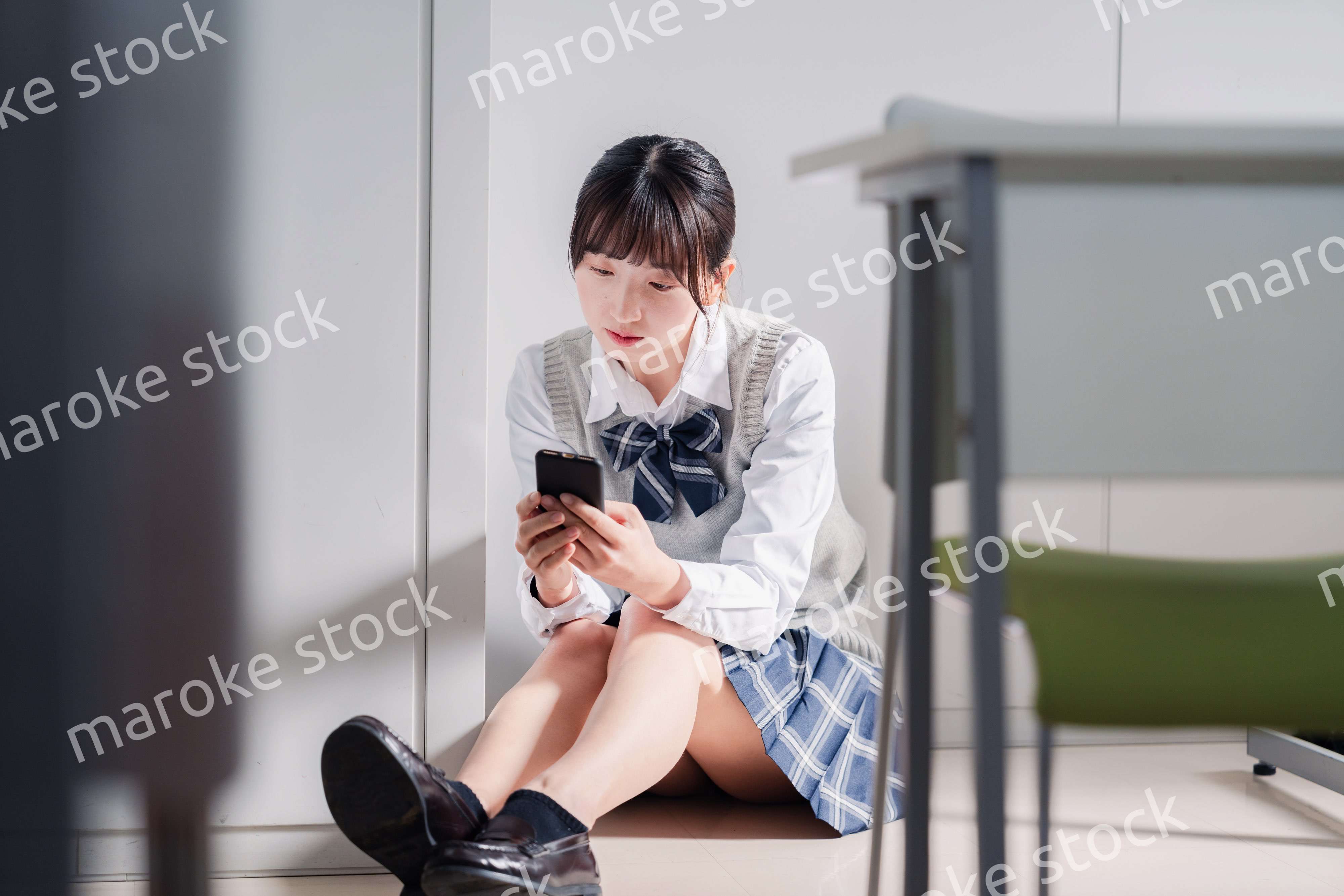 スマホを見ながら落ち込む女子高生