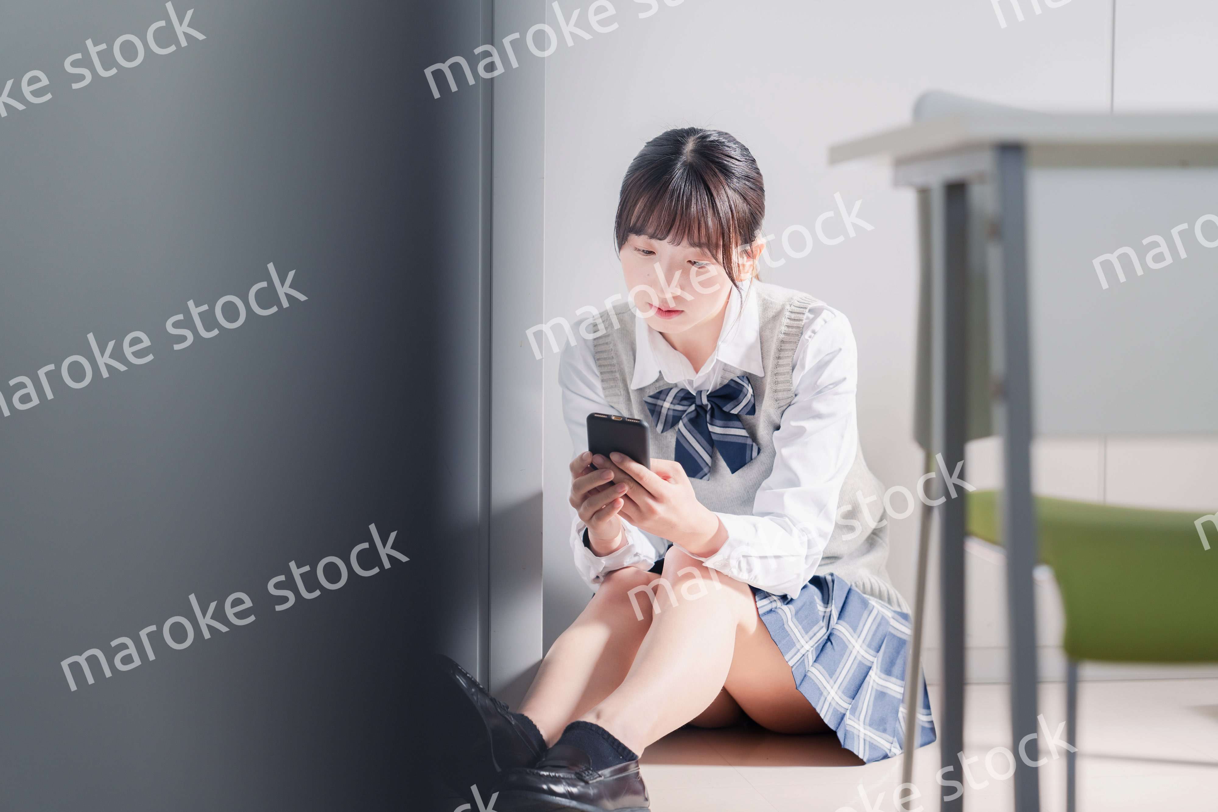 スマホを見ながら落ち込む女子高生