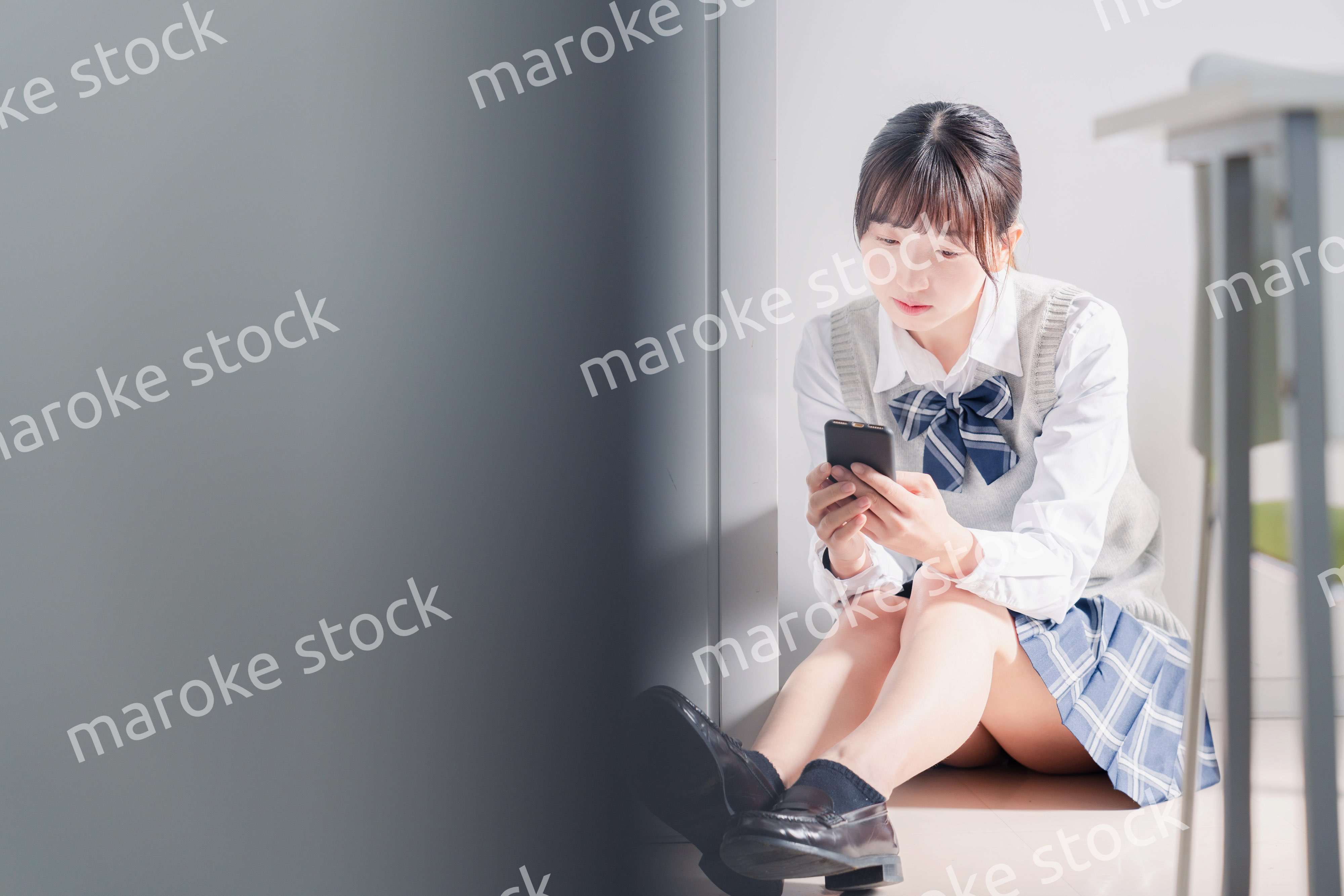 スマホを見ながら落ち込む女子高生