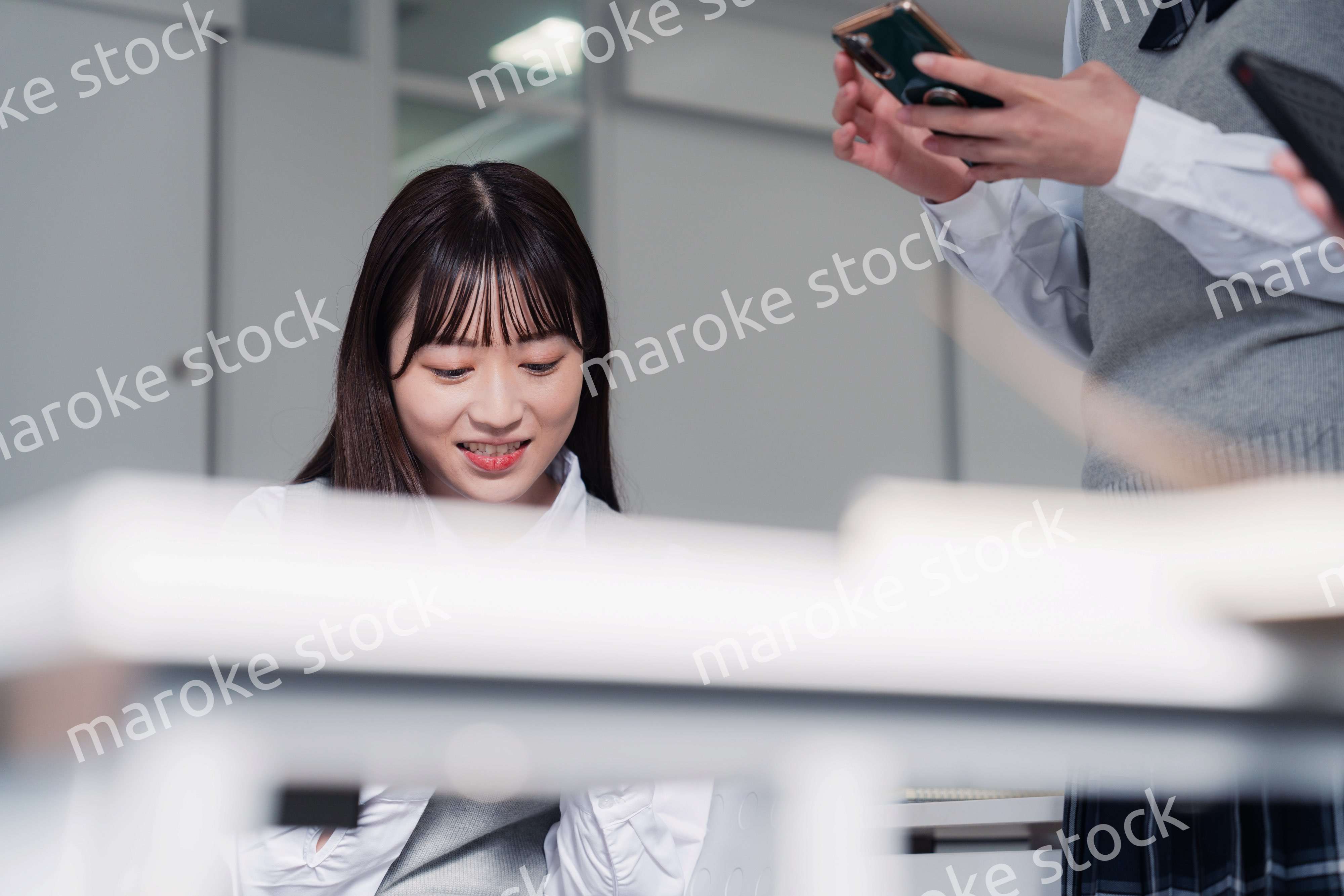 教室でスマホを見ながら話す女子高生