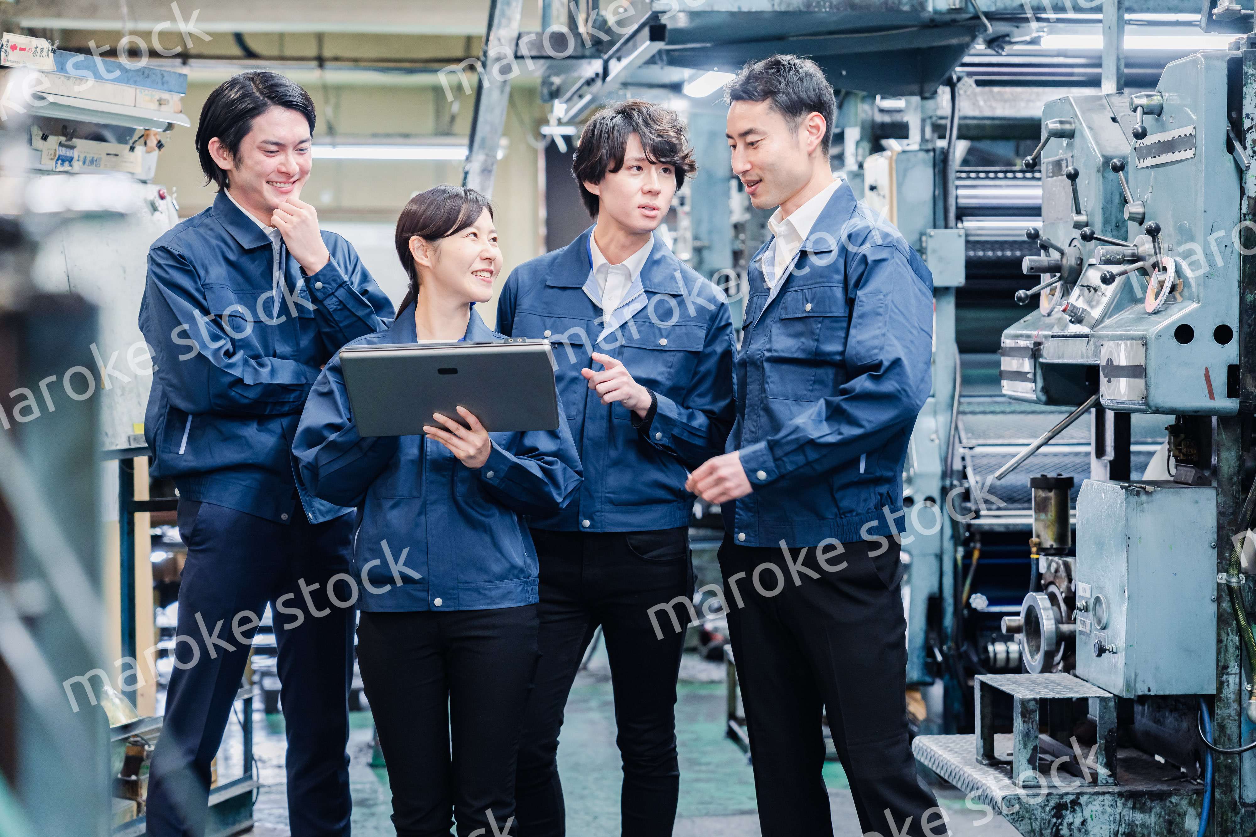 タブレット端末を見ながら会議をする工場スタッフ