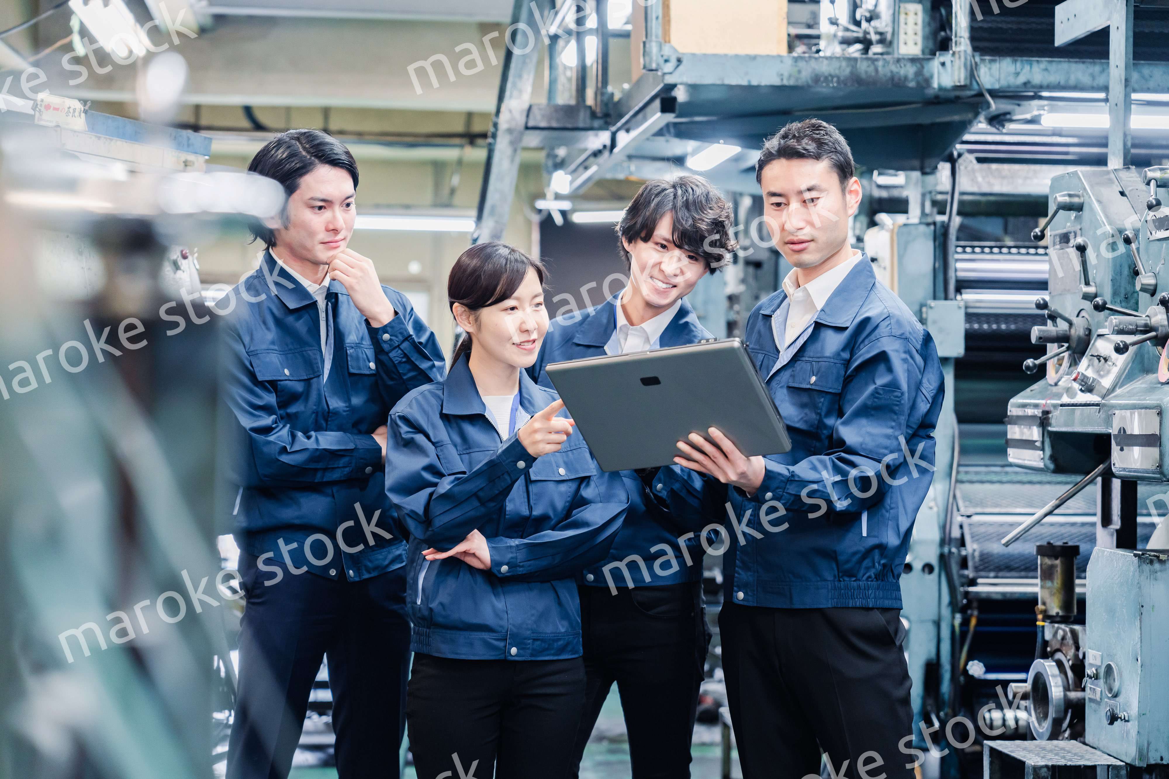 タブレット端末を見ながら会議をする工場スタッフ