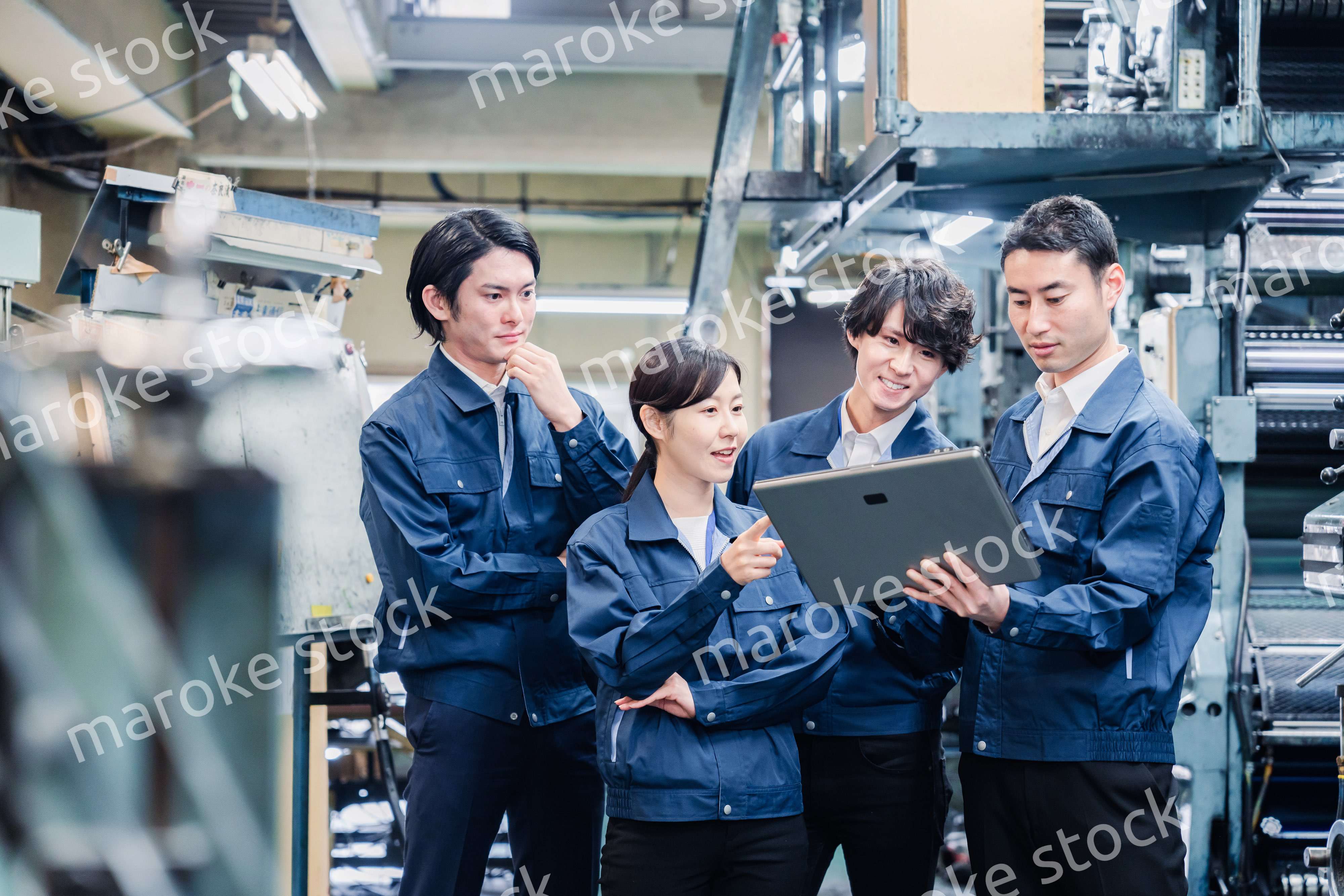 タブレット端末を見ながら会議をする工場スタッフ