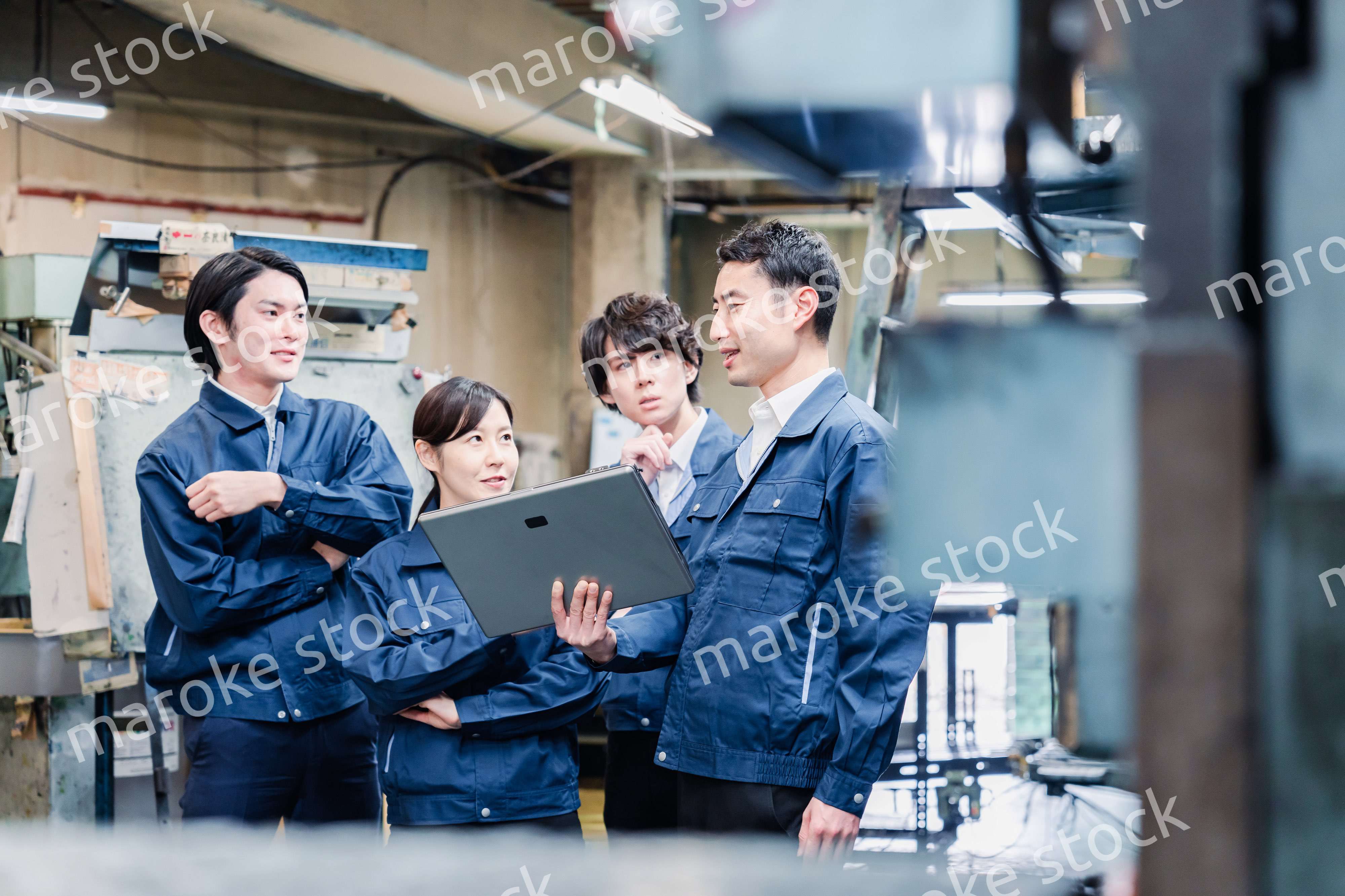 タブレット端末を見ながら会議をする工場スタッフ