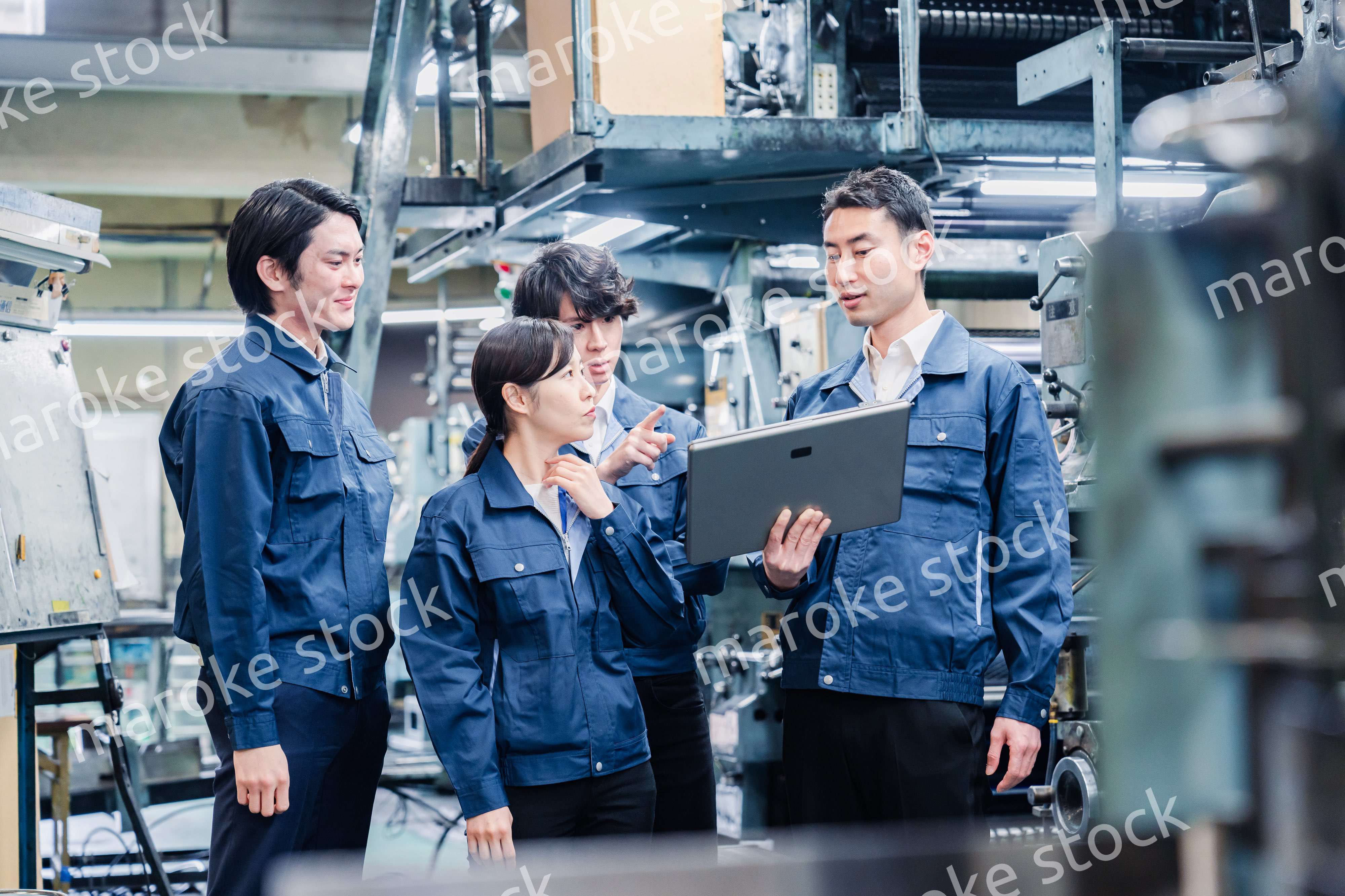 タブレット端末を見ながら会議をする工場スタッフ